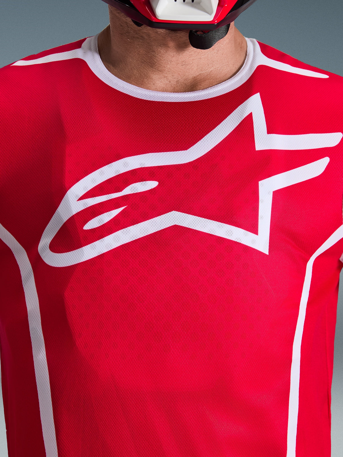 Close-up of Alpinestars 2026 Fluid Apex Jersey in Red and White, featuring a large white Astars logo on the chest, breathable polyfabric mesh construction, and white collar trim, motocross racing apparel.