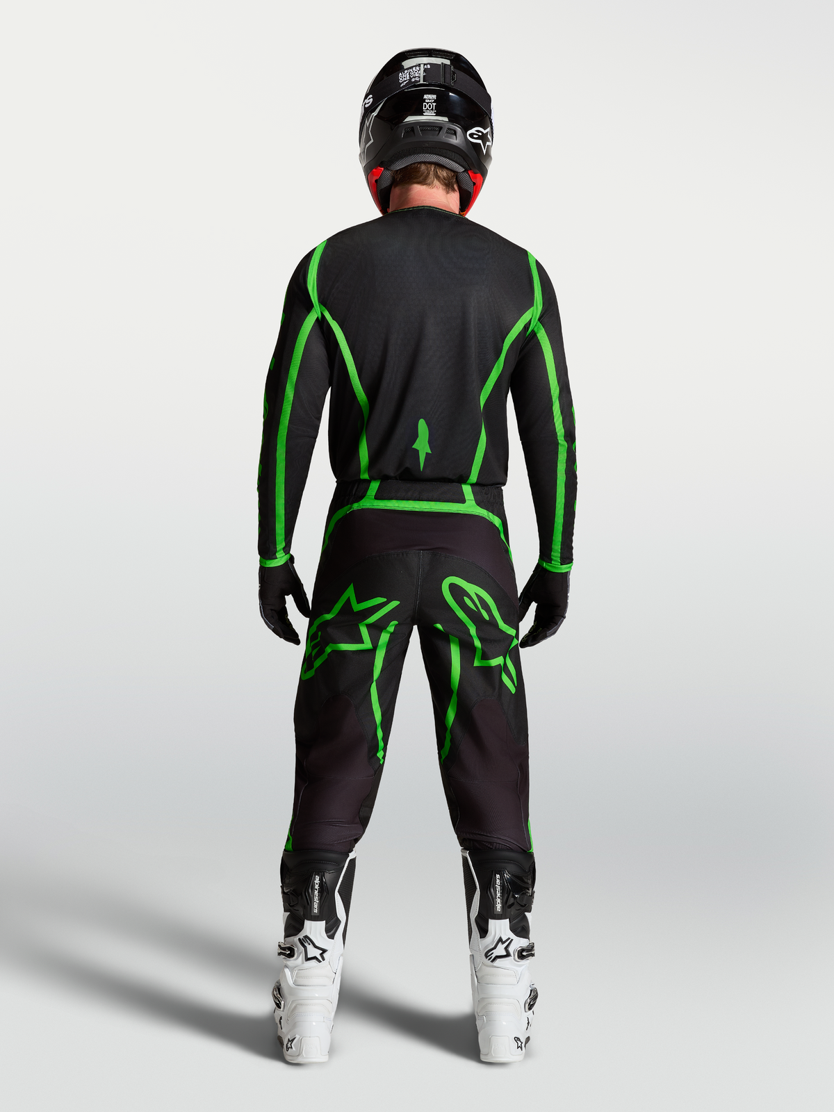 Alpinestars Fluid Apex V2 Jersey, motocross performance gear, black and green fluo, rear view on rider with white boots.