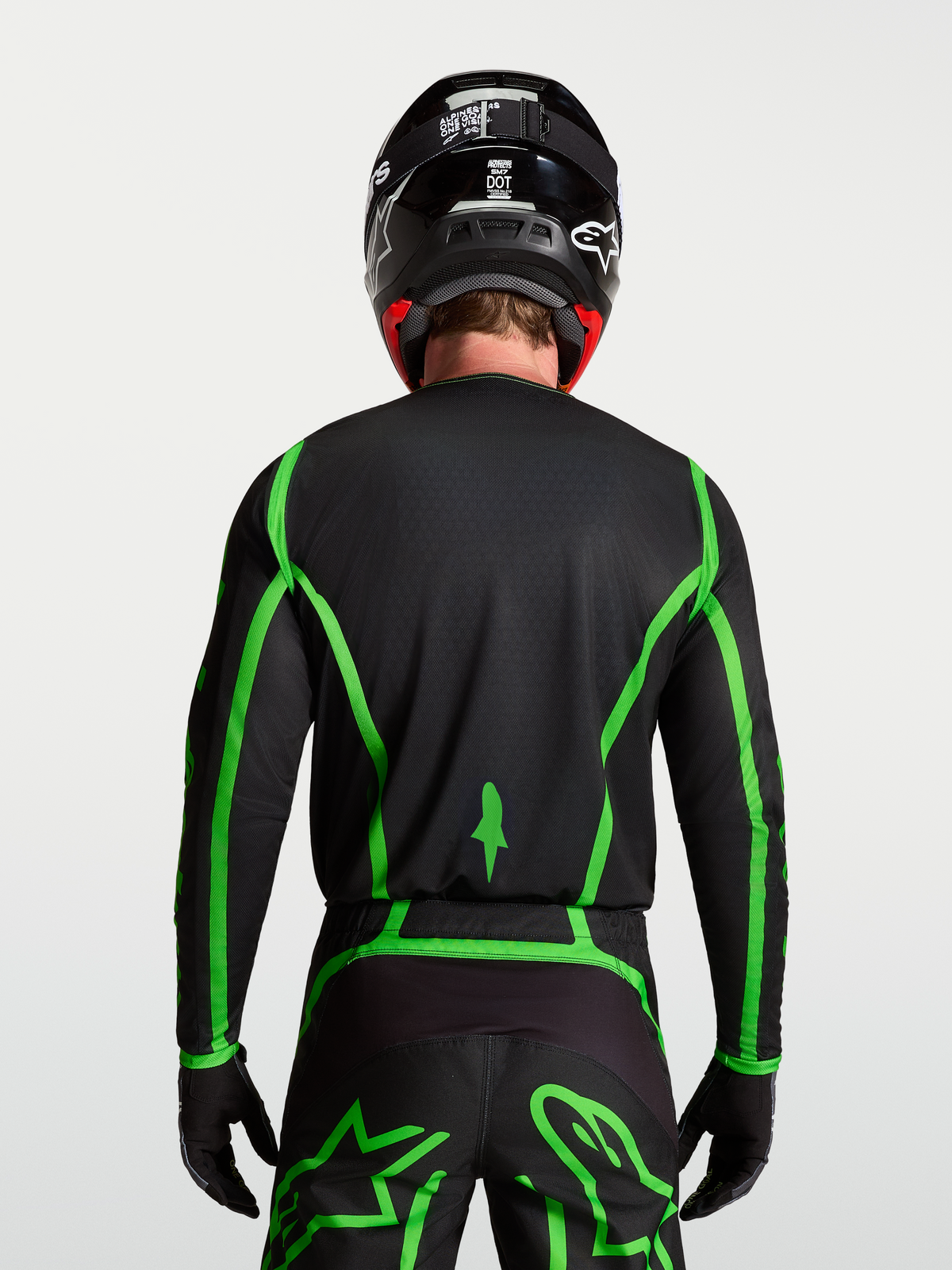 Alpinestars Fluid Apex V2 Jersey for motocross, black and fluorescent green, rear view on model showing extended back coverage.