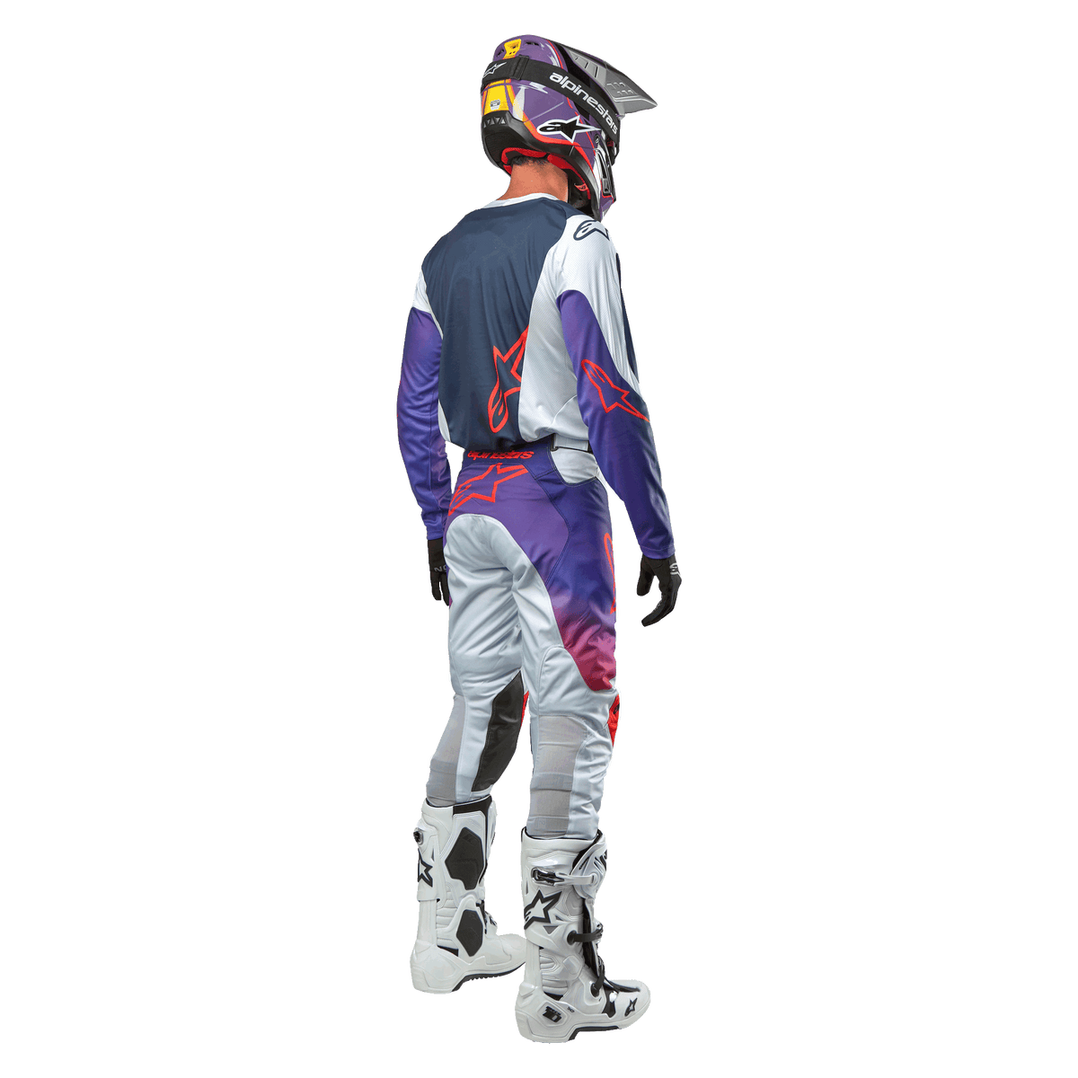 Motocrosskører set bagfra iført Alpinestars 2024 Racer Hoen Jersey i farven Light Gray Hot Orange Black, marineblåt rygpanel med orange stjernelogo, lilla ærmer, matchende racerbukser og hvide støvler.