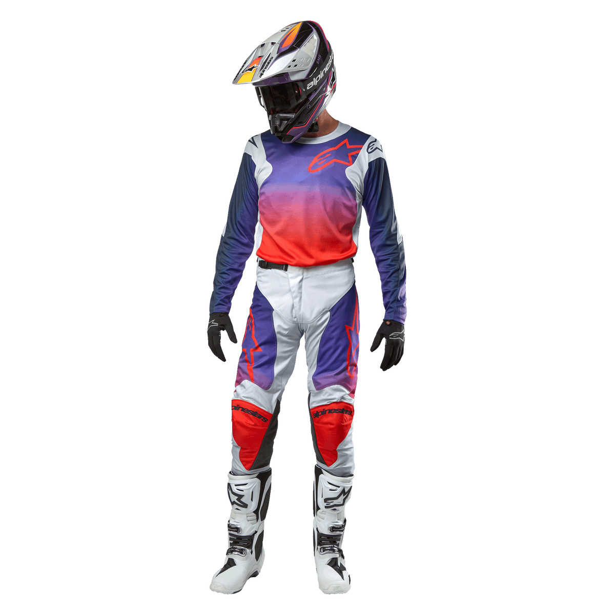 Motocross-kører iført komplet racerudstyr, Alpinestars 2024 Racer Hoen-trøje med lilla til neonorange farveovergang og lysegrå skuldre, matchende lysegrå bukser med røde og lilla detaljer, koordineret hjelm og hvide støvler, komplet terrænracerudstyr