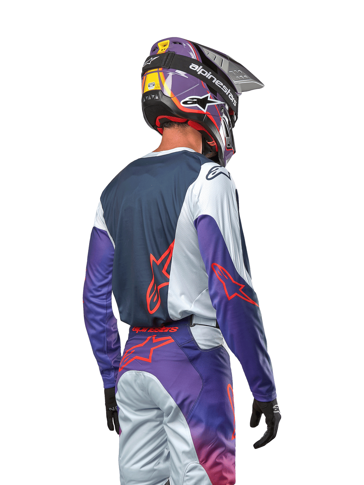 Motocrosskører set bagfra iført 2024 Racer Hoen Jersey, marineblåt rygpanel med lysegrå skuldre og lilla ærmer, stærkt orange Alpinestars-logoer, matchende lilla og grå bukser med en lilla motocrosshjelm, komplet off-road racersæt