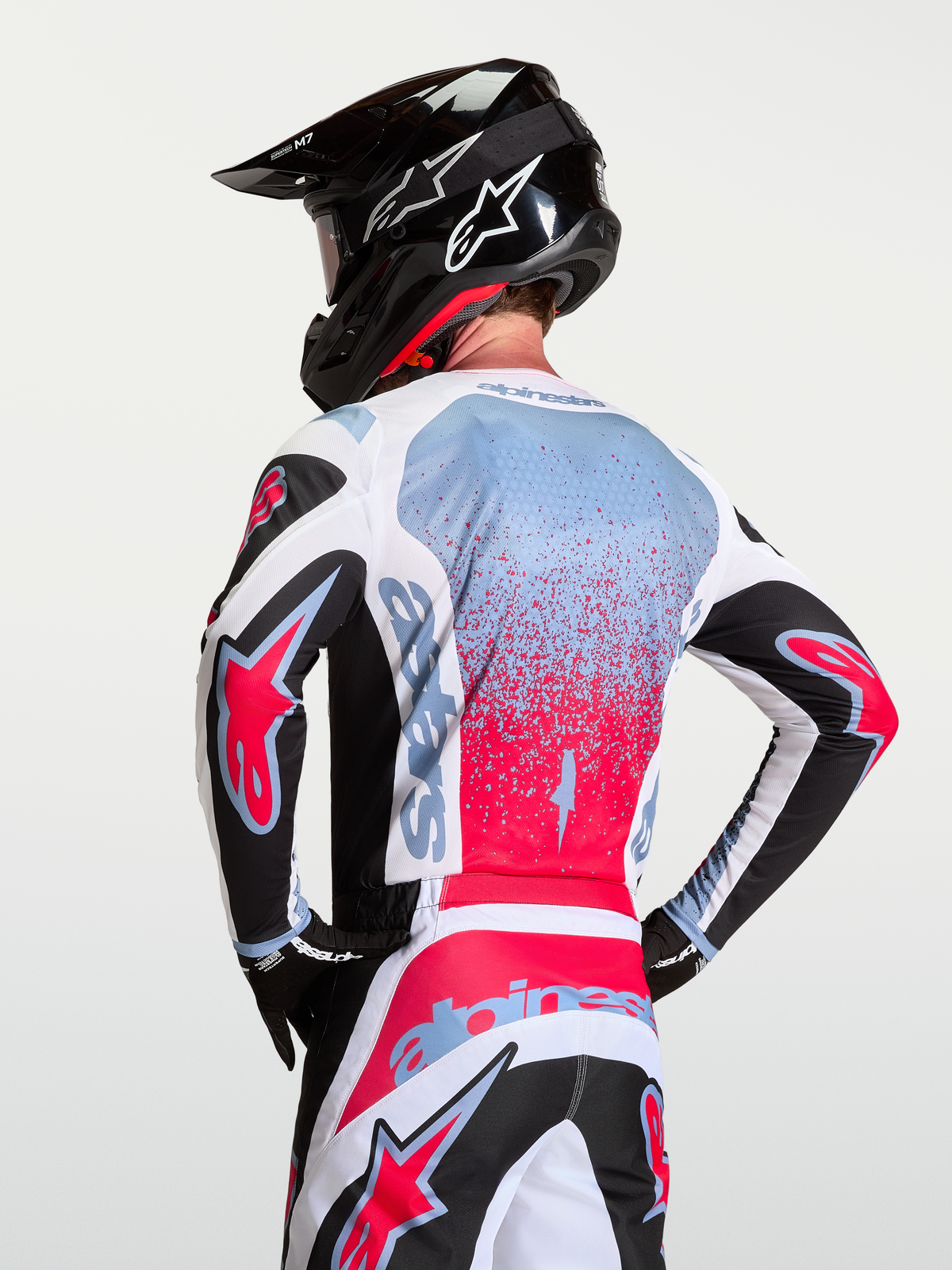 Alpinestars Fluid Drag trøje, motocrossudstyr til herrer, sort, hvid og rød med lyseblå detaljer, set bagfra med åndbart polyfabrik, on-model med hjelm