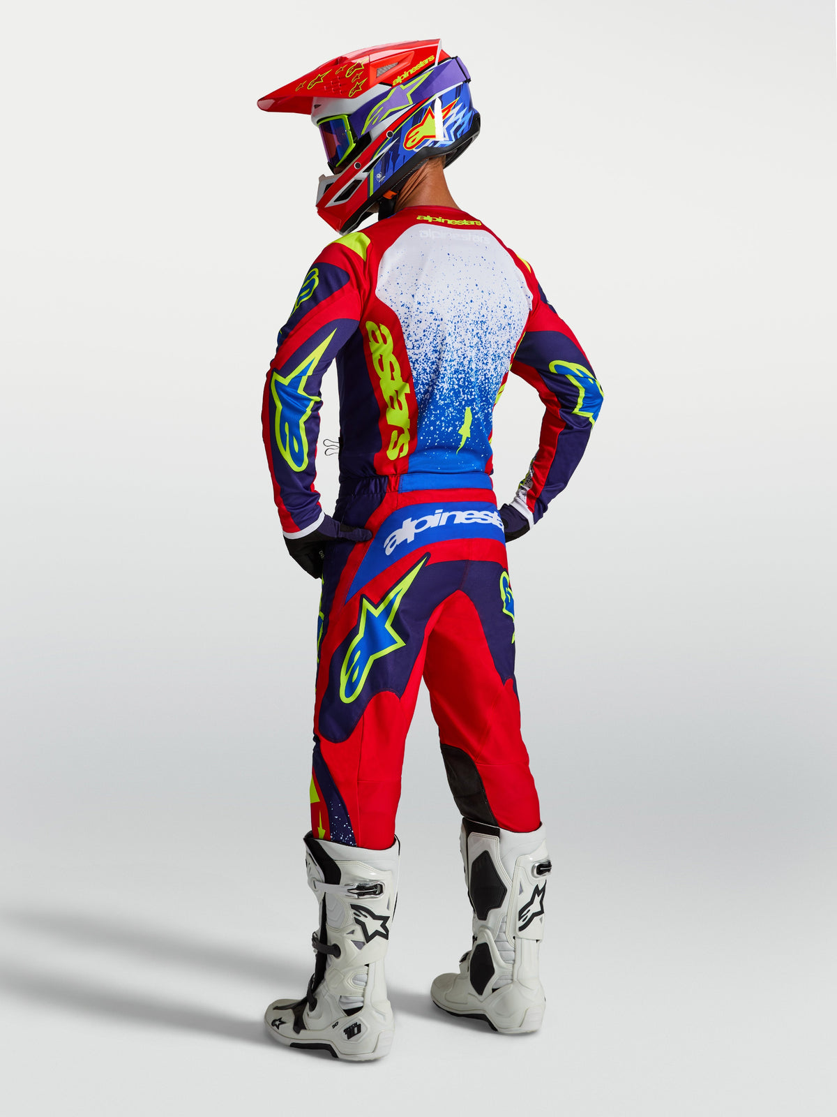 Alpinestars Fluid Drag Trøje, blå og rød motocrosstrøje til herrer, set bagfra med matchende udstyr og hvide støvler.