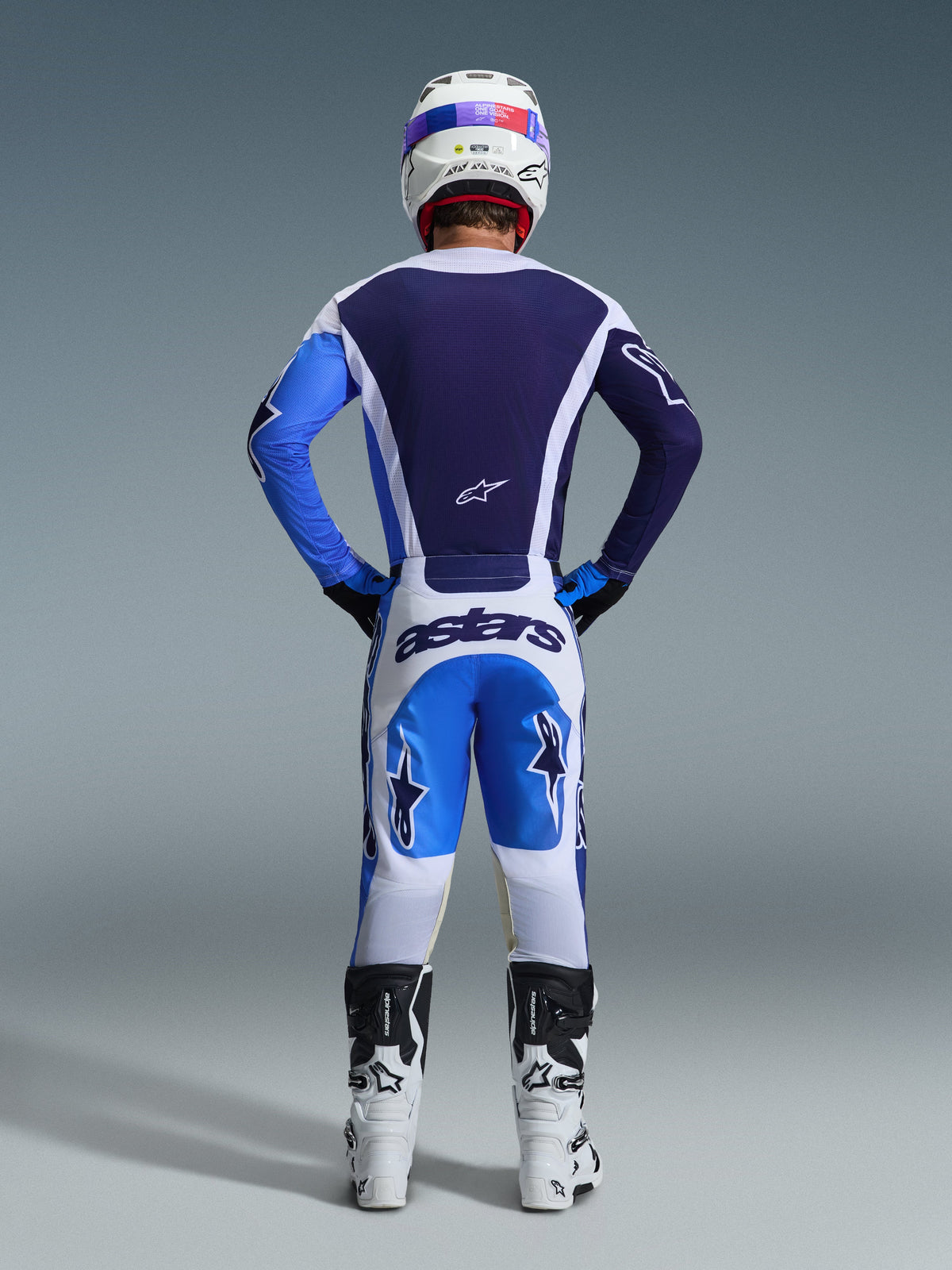Alpinestars 2026 Racer Air Portl Jersey i Ucla Blue White, set bagfra på en motocrosskører, kombineret med matchende hvide og blå bukser og hvide støvler, der fremhæver den fulde mesh-konstruktion med luftgennemstrømning på ryggen til off-road racing.