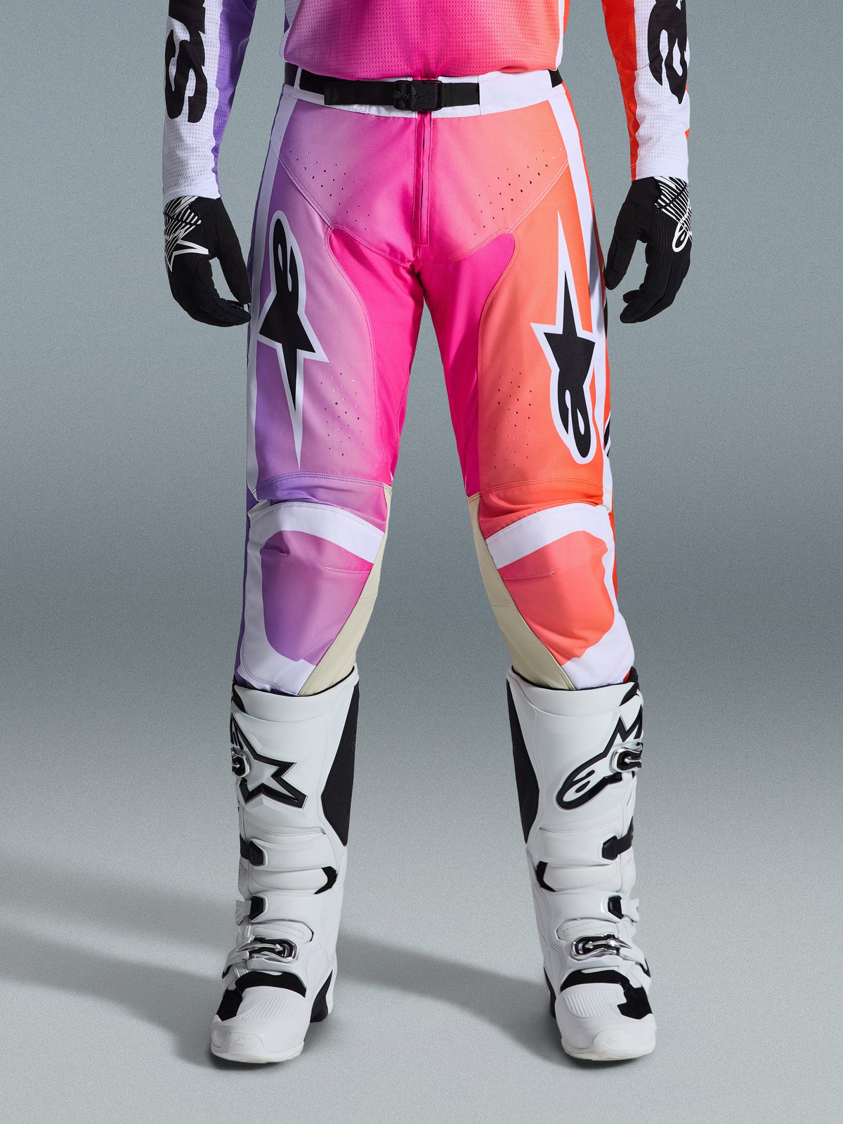 Alpinestars 2026 Racer Air Portl bukser, motocross-bukser, levende lilla, pink og orange gradient, med markante stjernelogoer på lårene, båret med hvide racerstøvler og sorte handsker, designet til højpræstations terrænkørsel.