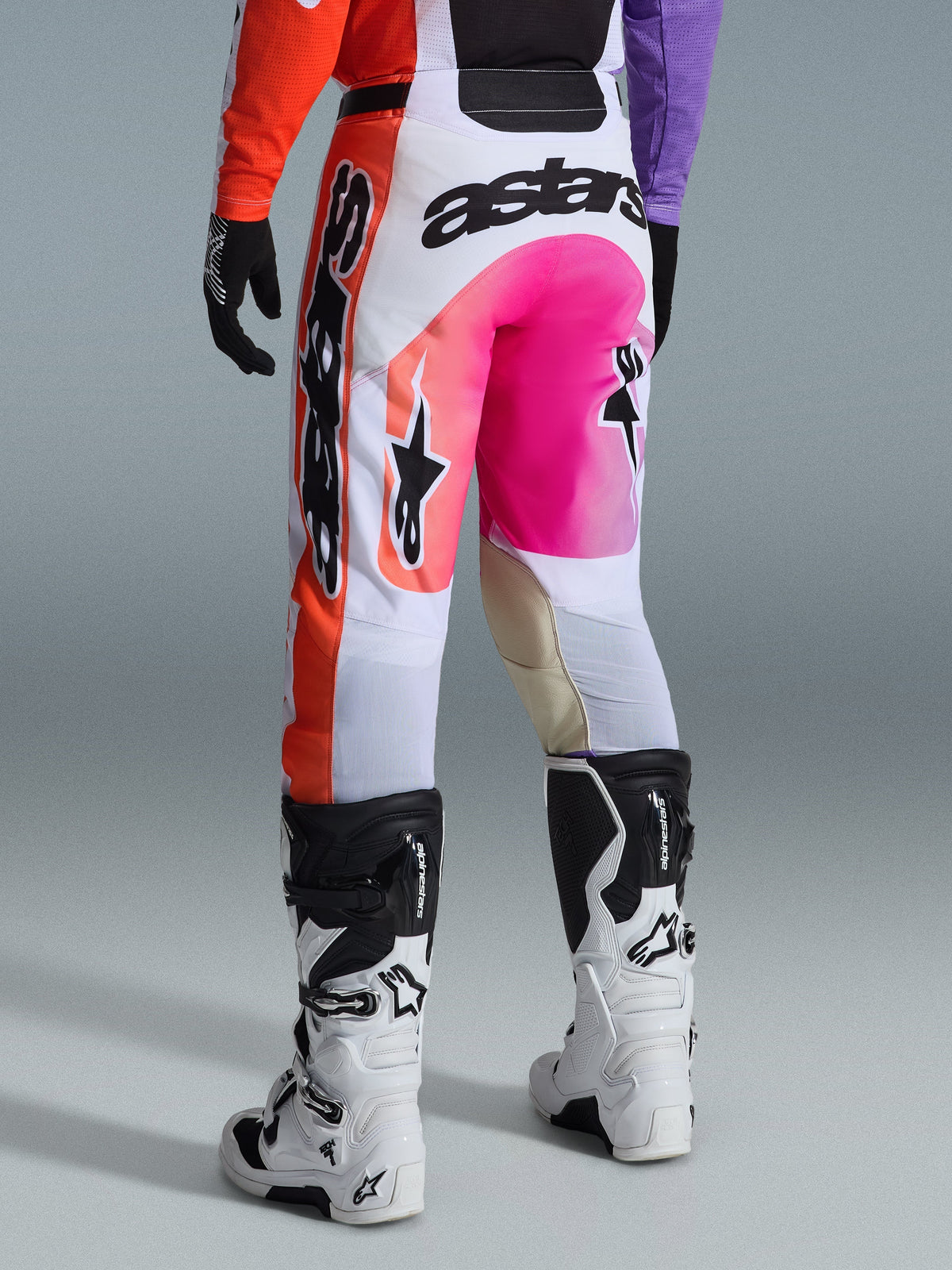 Alpinestars 2026 Racer Air Portl bukser, motocrossbukser, multifarvet med hvid, stærk lyserød og orange, set bagfra med hvide og sorte Alpinestars-støvler, markant branding og holdbar racerkonstruktion