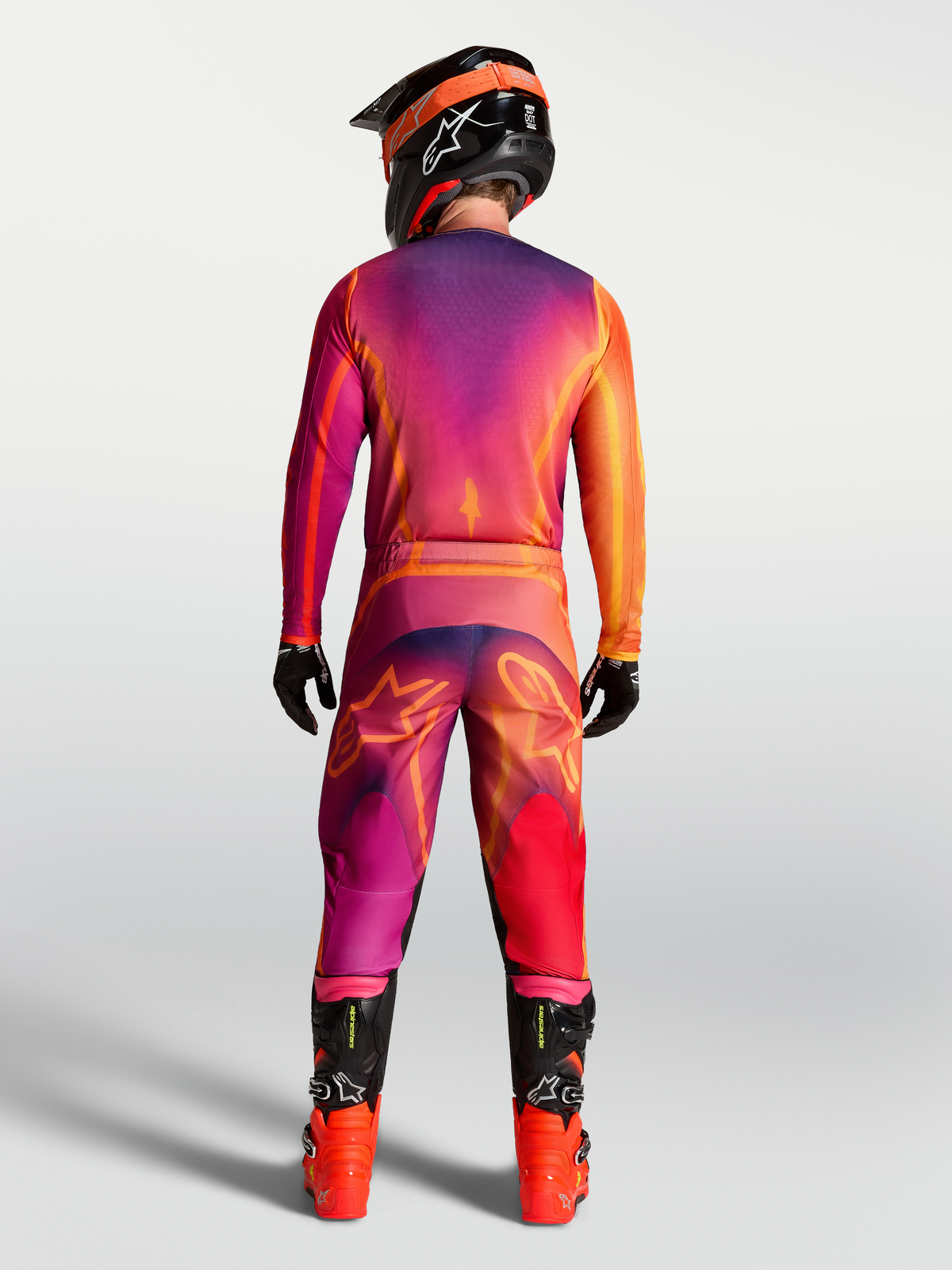 Alpinestars Fluid Kepler Bukser, motocrossbukser, lilla og orange, set bagfra på model med matchende trøje og støvler, sport-fit design i forstærket polyfabric til terrænkørsel.