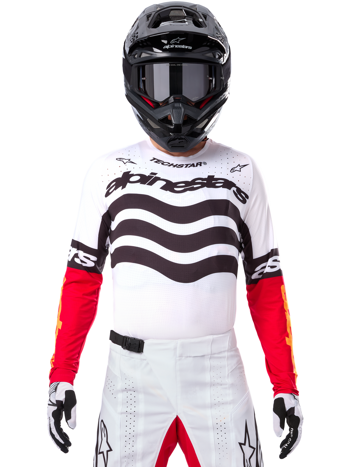 Motocrossrytter iført komplet racerudstyr, Limited Edition Techstar Deep-trøje i hvid og sort med røde ærmer, med bølgegrafik og markant Alpinestars-branding, hvide motocrossbukser, sort hjelm og beskyttelsesbriller, koordineret outfit til off-road racing