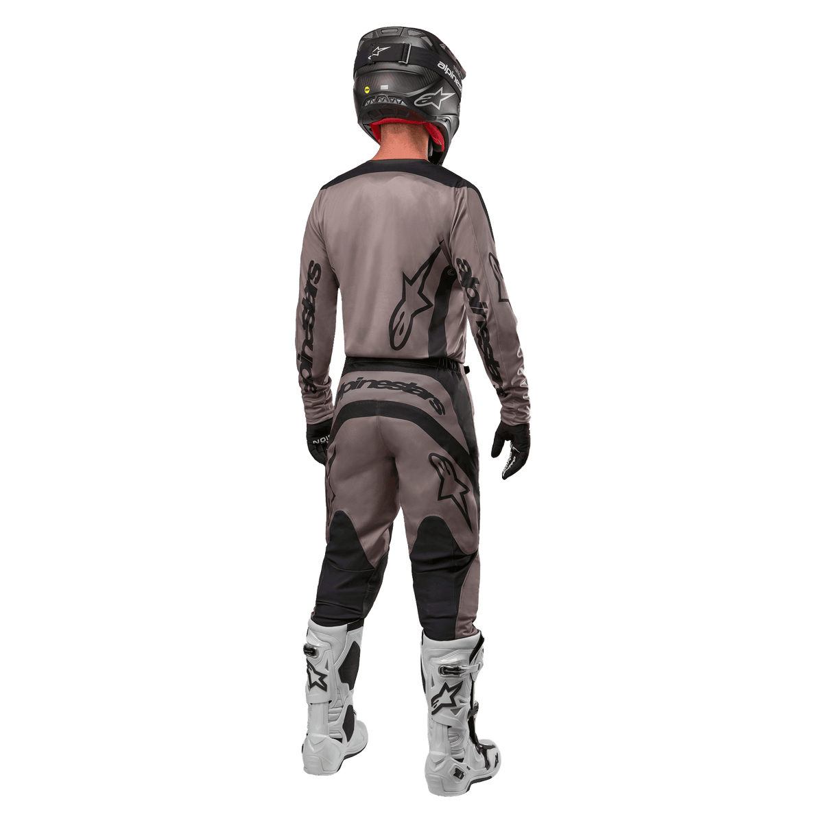 Alpinestars 2024 Fluid Lurv trøje, motocross-trøje, Mud Black, set bagfra af motocross-rytter iført matchende racerudstyr, sort hjelm og hvide støvler, med markante sorte Alpinestars-logoer og en atletisk pasform til off-road kørsel.