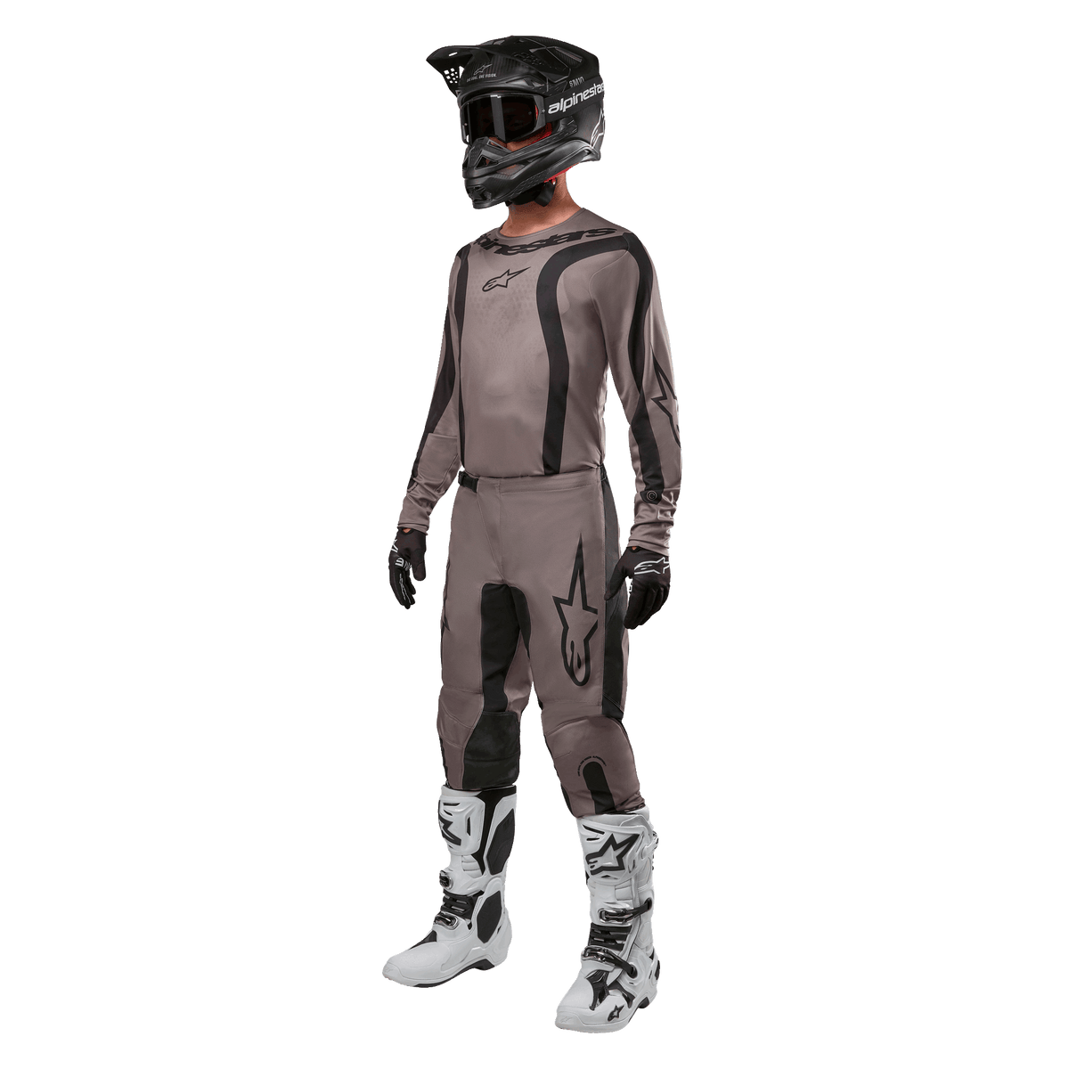 Alpinestars motocross-rytter iført komplet racerudstyr med 2024 Fluid Lurv trøje i Mud Black, matchende bukser, sort hjelm med goggles, hvide og sorte støvler samt sorte handsker, koordineret outfit til off-road racing