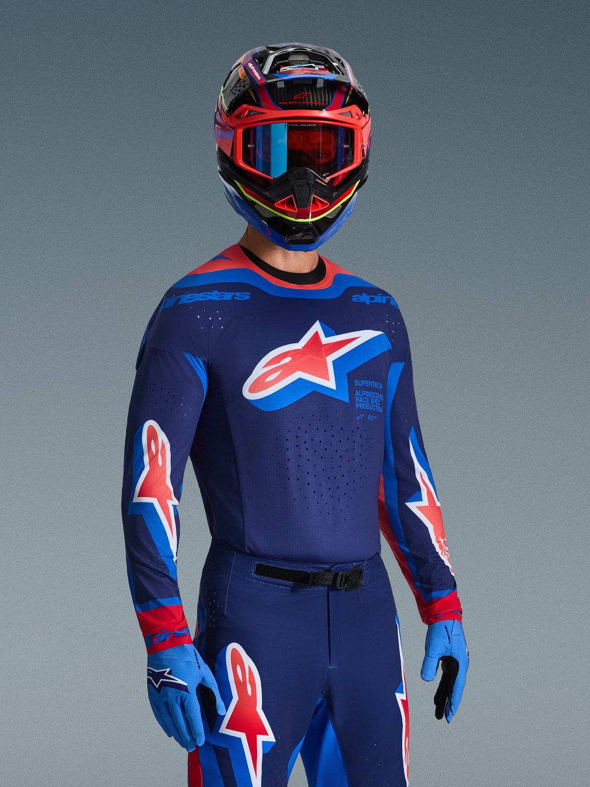 Alpinestars 2026 Supertech Vista udstyrssæt, motocrosskører iført mørkeblå jersey med lyseblå og røde detaljer og et stort stjernelogo på brystet, matchende bukser og handsker, flerfarvet hjelm med blå og røde goggles, professionelt racerudstyr