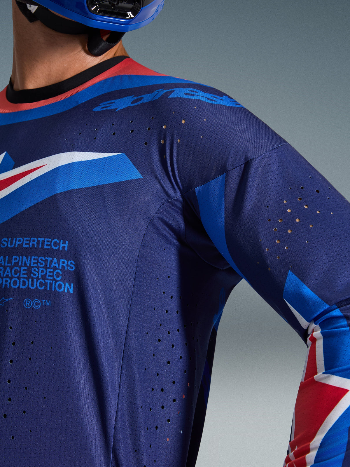 Alpinestars 2026 Supertech Vista Jersey, nærbillede af mørkeblå og koboltblå trøje med Hot Coral-krave, med laser-skårne ventilationsperforeringer og Alpinestars Race Spec-branding, premium atletisk mesh-konstruktion til motocross-racing