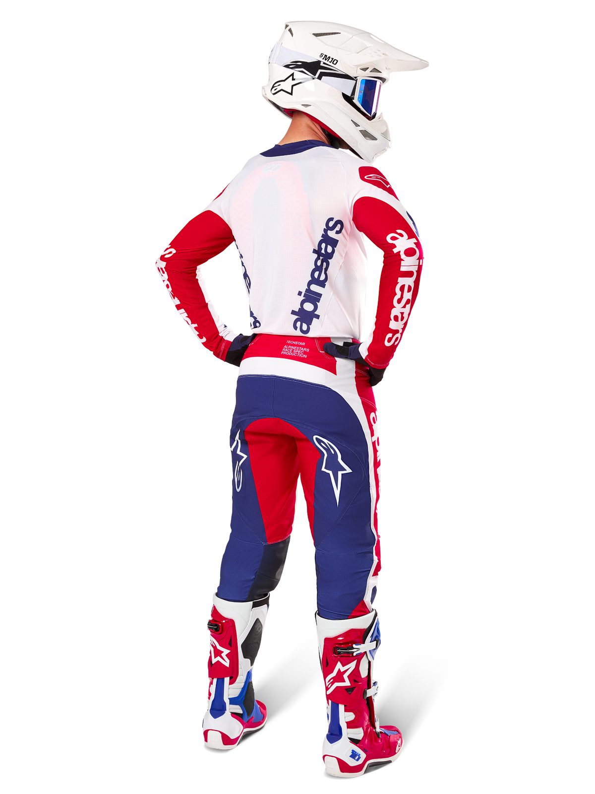 Motocrosskører set bagfra iført Alpinestars Limited Edition Techstar Fortitude Jersey, klar rød, hvid og blå farvekombination, matchende tekniske bukser med stjernelogoer, hvid hjelm med goggles og røde og hvide støvler, komplet koordineret udstyr til off-road racing