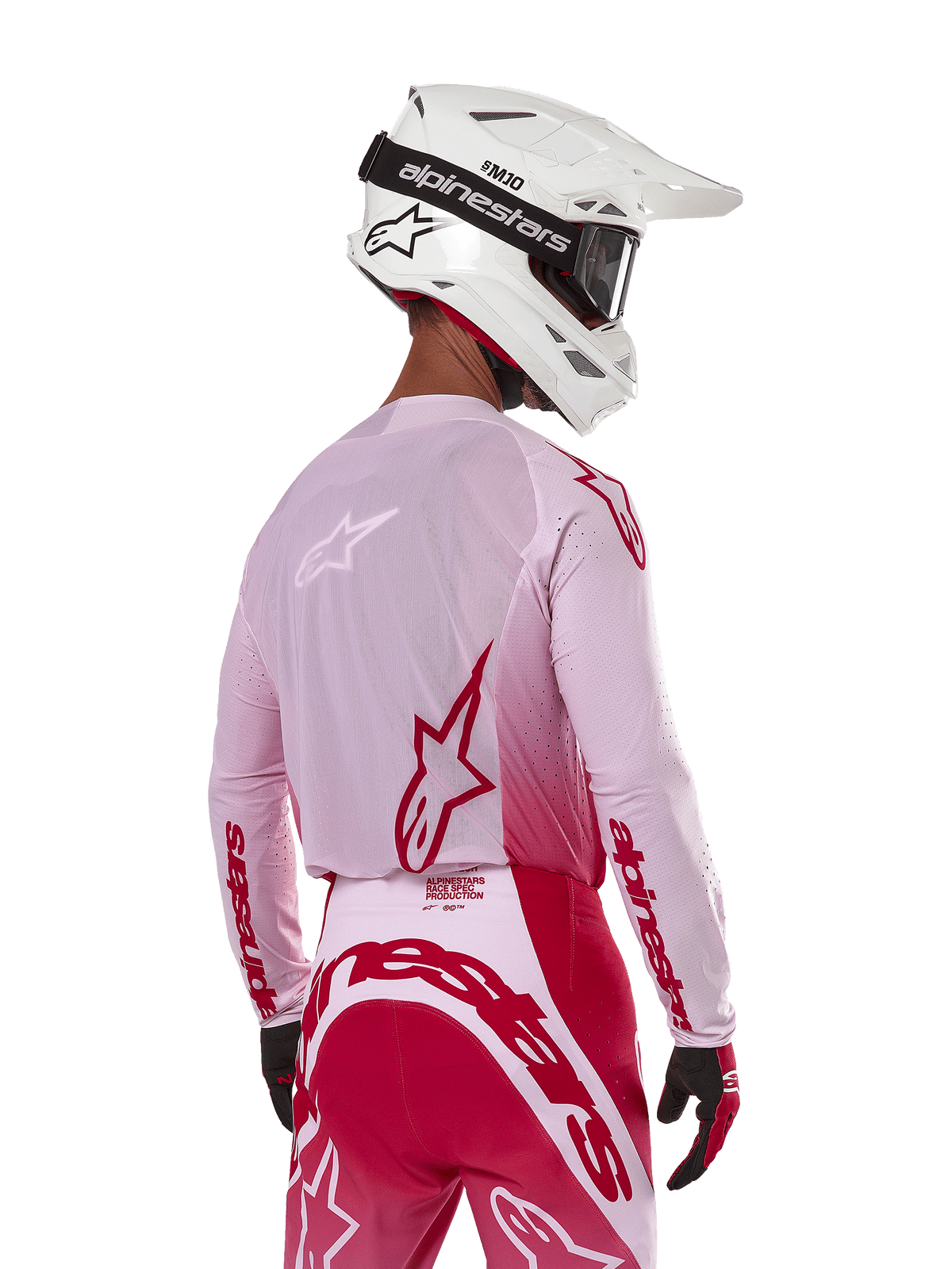 Motocrossrytter set bagfra iført Alpinestars 2024 Supertech Dade Jersey i Red Berry Lilac, med åndbare mesh-paneler og røde Alpinestars-logoer, kombineret med matchende røde og lilla bukser og en hvid Alpinestars-hjelm med goggles, professionelt off-road racerudstyr