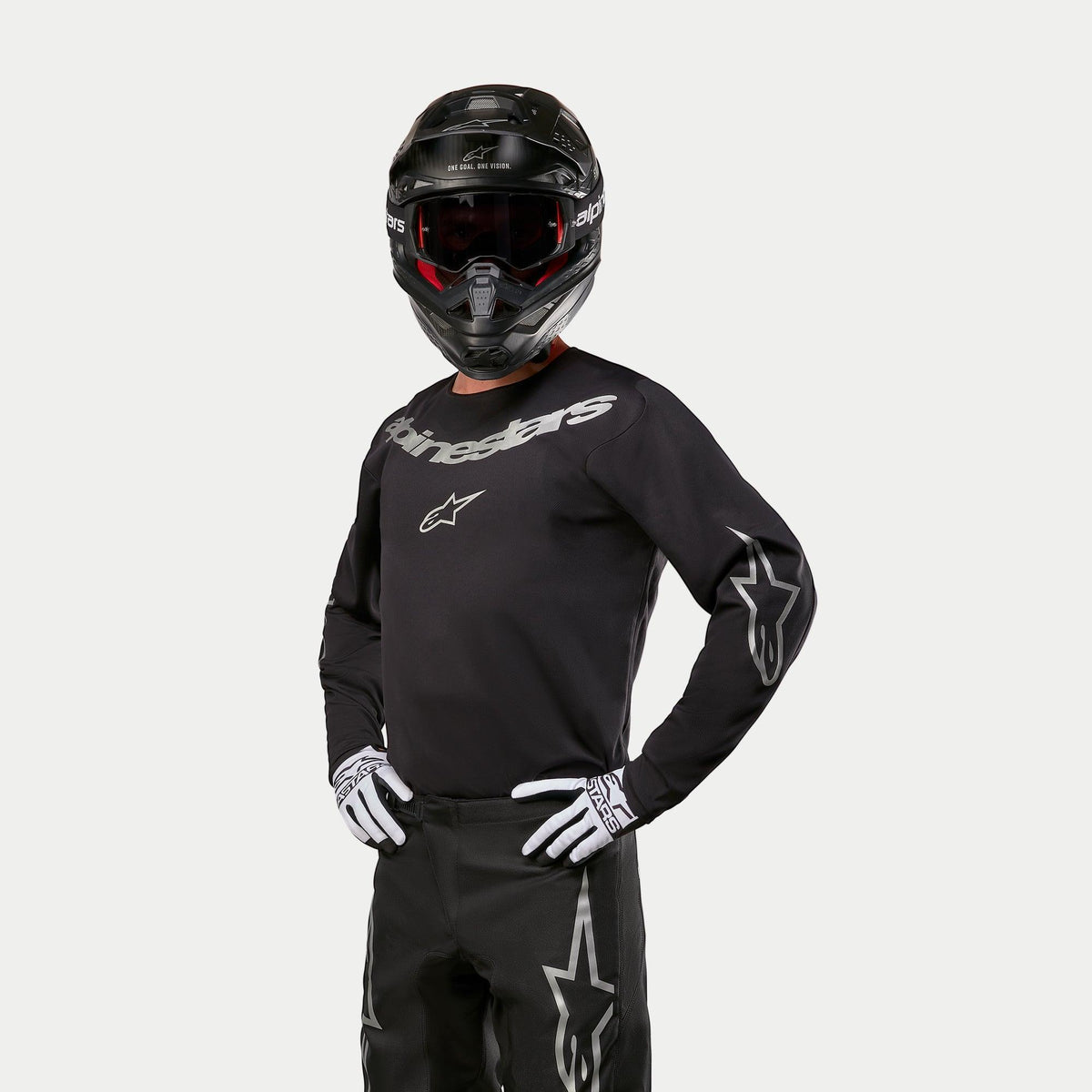 Alpinestars 2024 Fluid Graphite Jersey, motocross-trøje i sort og sølv, kombineret med sorte motocross-bukser, sort hjelm med rødtonede briller og hvid-sorte handsker, sølvfarvede logoer på bryst og ærmer