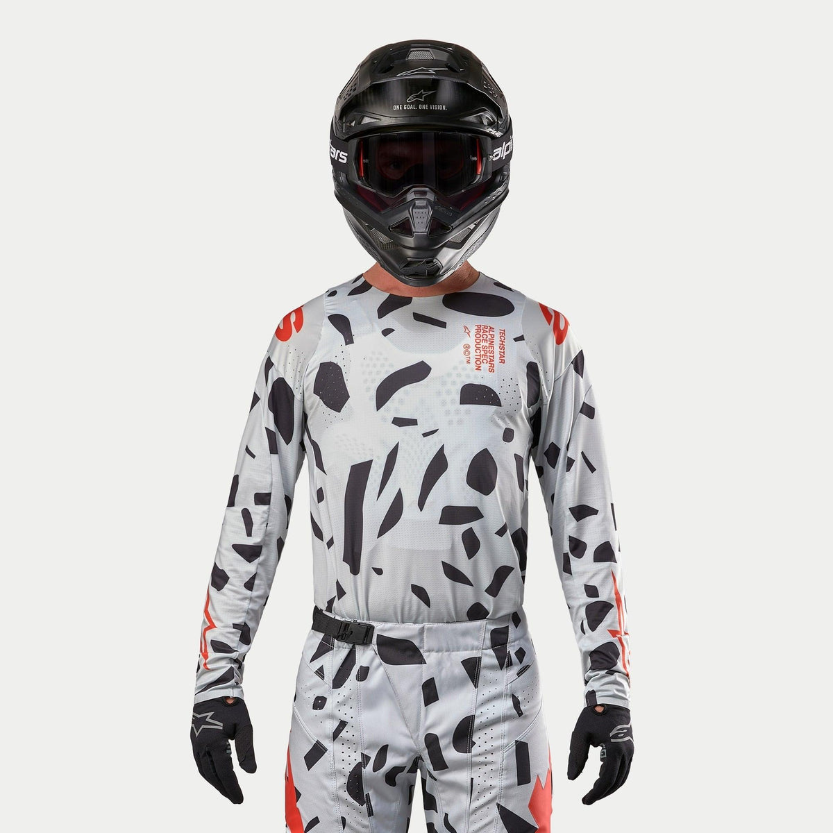Alpinestars 2024 Techstar Rantera jersey, motocross-trøje, Haze Gray Camo med sorte uregelmæssige mønstre og røde detaljer, båret af en kører med matchende bukser, sort hjelm og handsker, off-road racerudstyr