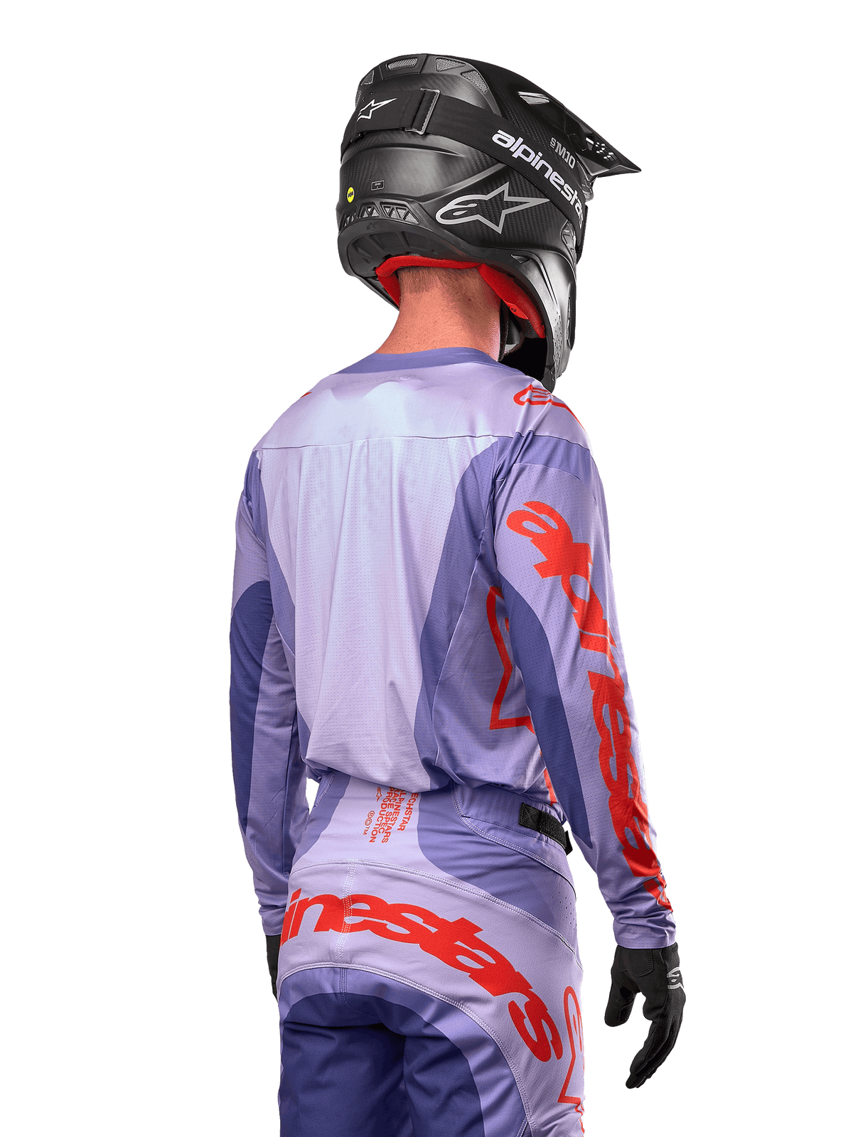 Alpinestars 2024 Techstar Ocuri Jersey, motocross-trøje, lilla og stærk orange, set bagfra på en kører iført matchende udstyr og sort hjelm, med store orange Alpinestars-bogstaver på ærmerne og den nederste del af ryggen