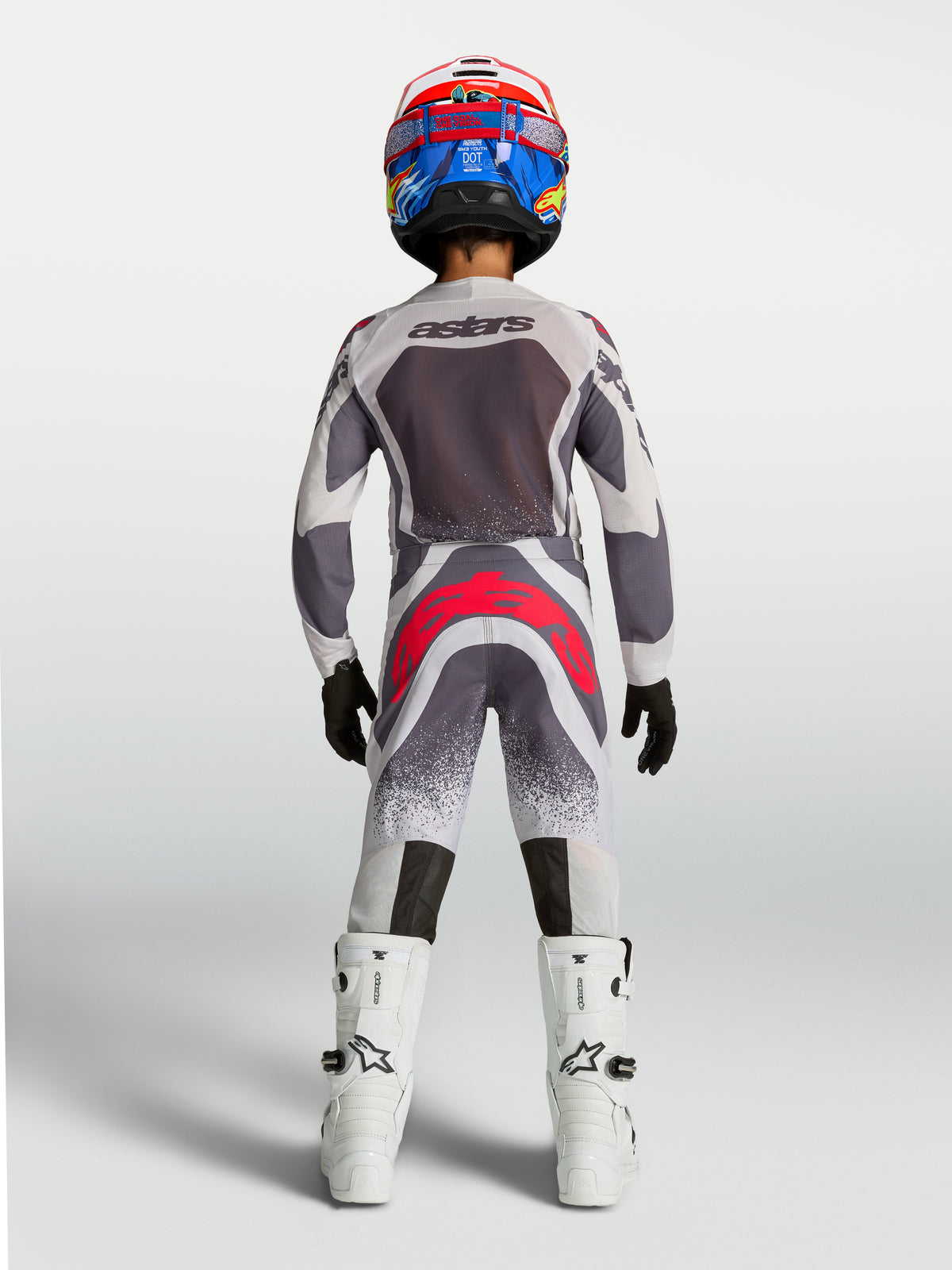 Alpinestars 2027 Supertech Swan trøje og gear-sæt til ungdom, grå og hvidt motocross-udstyr med røde detaljer, set bagfra.