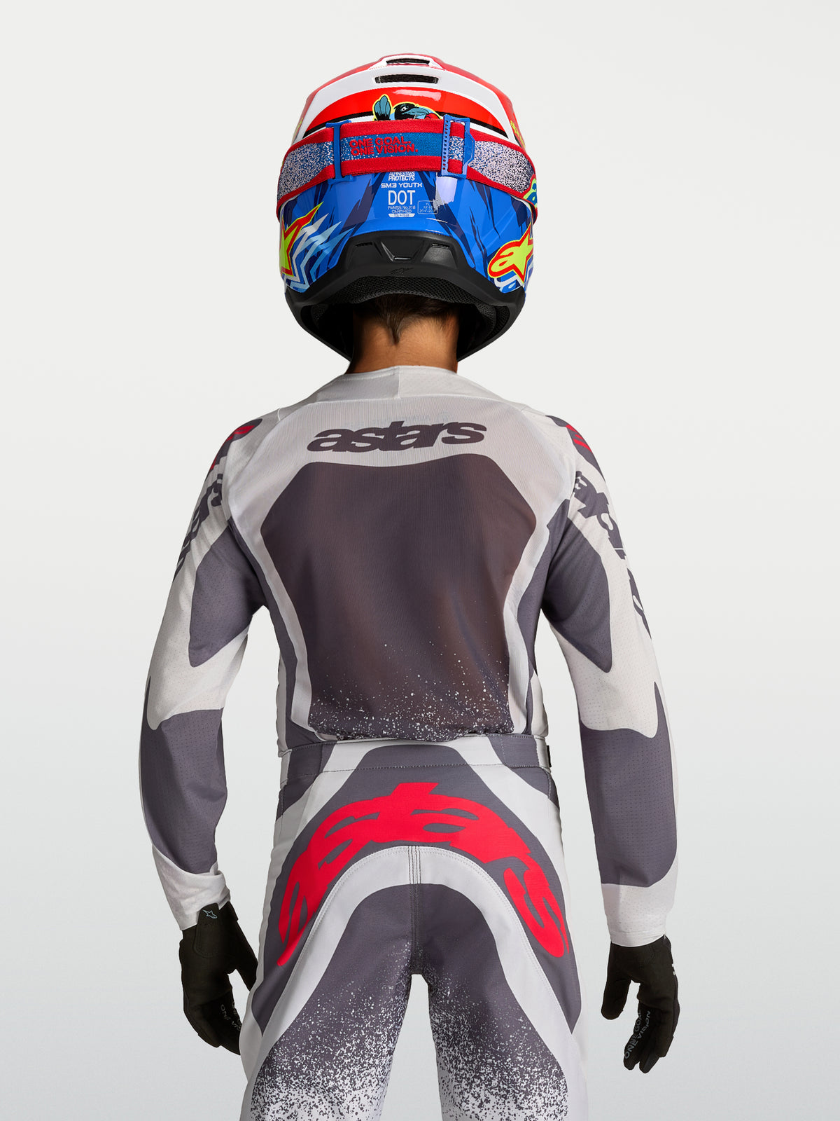 Alpinestars Supertech Swan motocross-trøje og bukser til ungdom, grå og hvid med neonrøde detaljer, set bagfra på model.