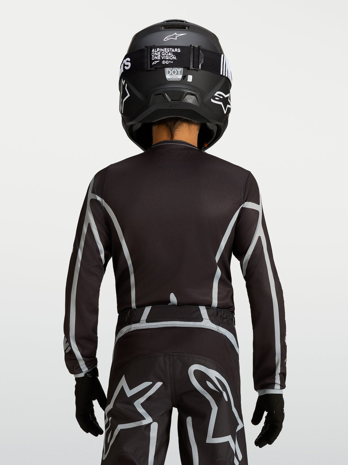 Alpinestars 2027 Fluid Apex V2 trøje til ungdom, sort og sølv motocrosstrøje med ergonomisk pasform og forlænget ryg.