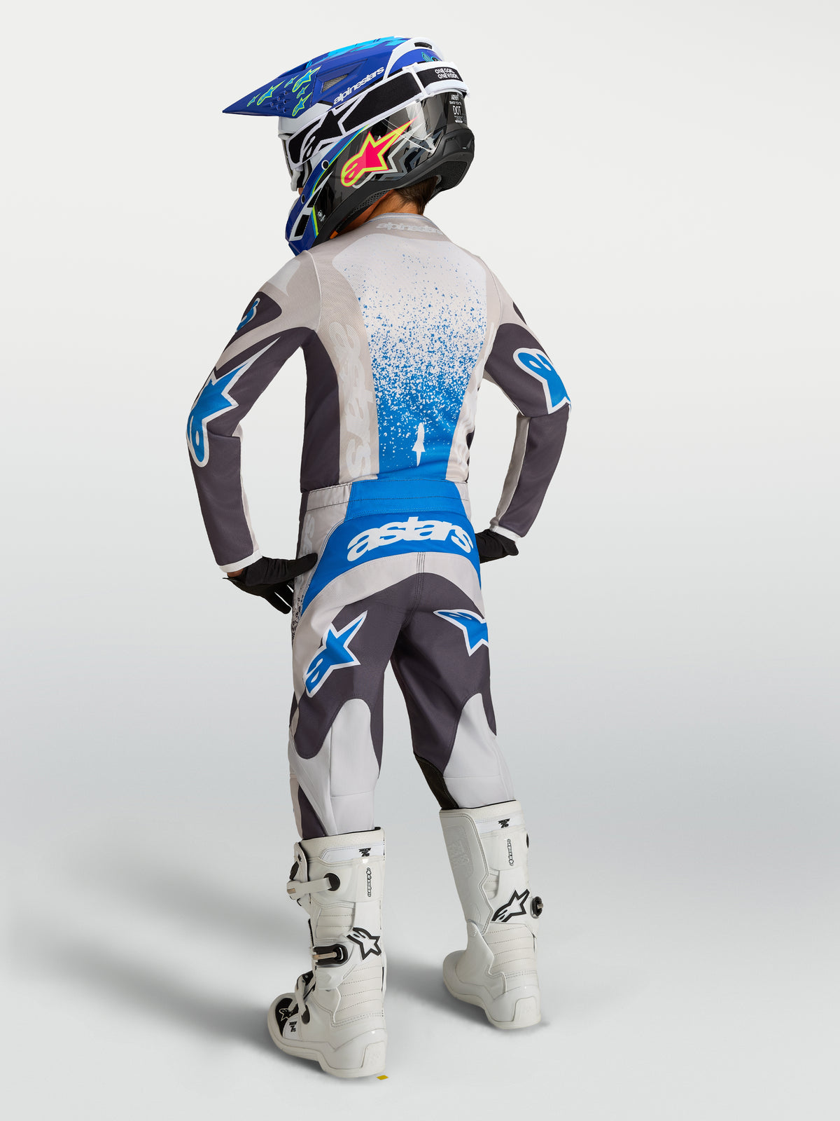 Alpinestars Youth Fluid Drag motocross jersey and pants in gray and blue, back view on a young rider.