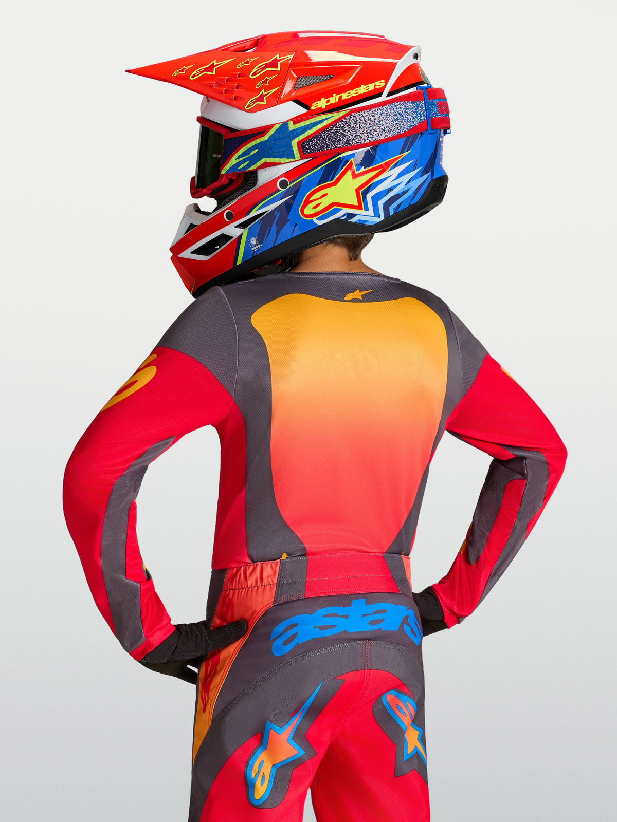 Alpinestars 2027 Fluid Hunt trøje til ungdom, rød og grå motocrosstrøje, fugttransporterende, set bagfra på en rytter.