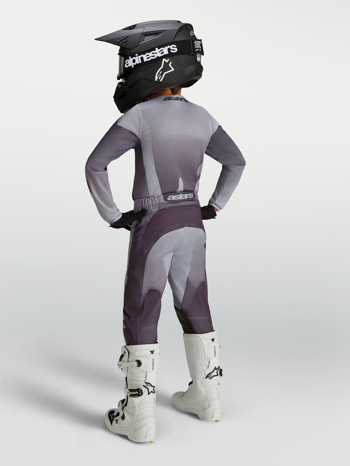 Alpinestars 2027 Fluid Amber trøje og gearsæt til ungdom, gråt og lilla motocrossudstyr med sort hjelm og hvide støvler.