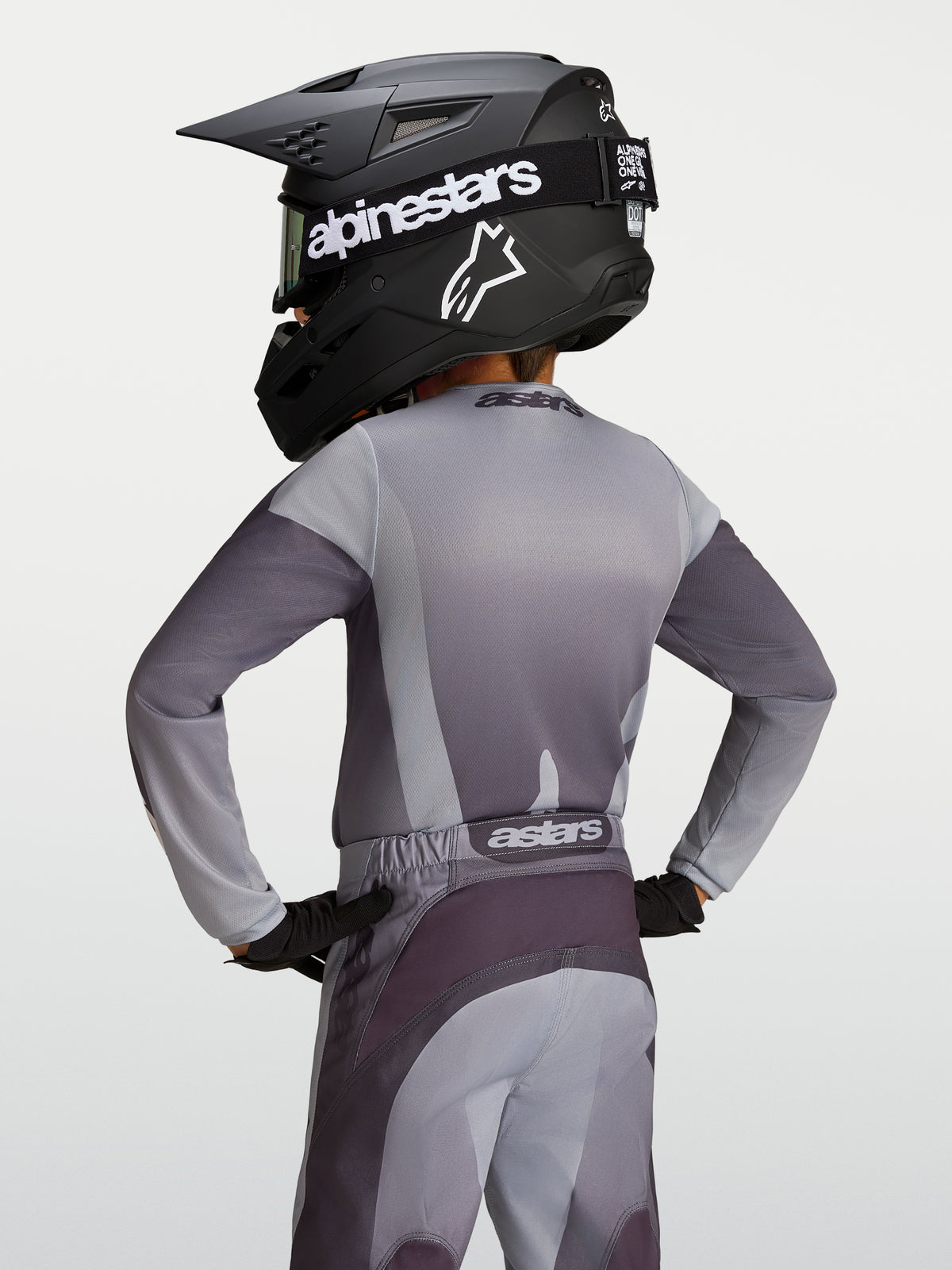 Alpinestars 2027 Fluid Amber trøje til unge, grå og sandfarvet fugttransporterende motocrosstrøje, set bagfra på en rytter.