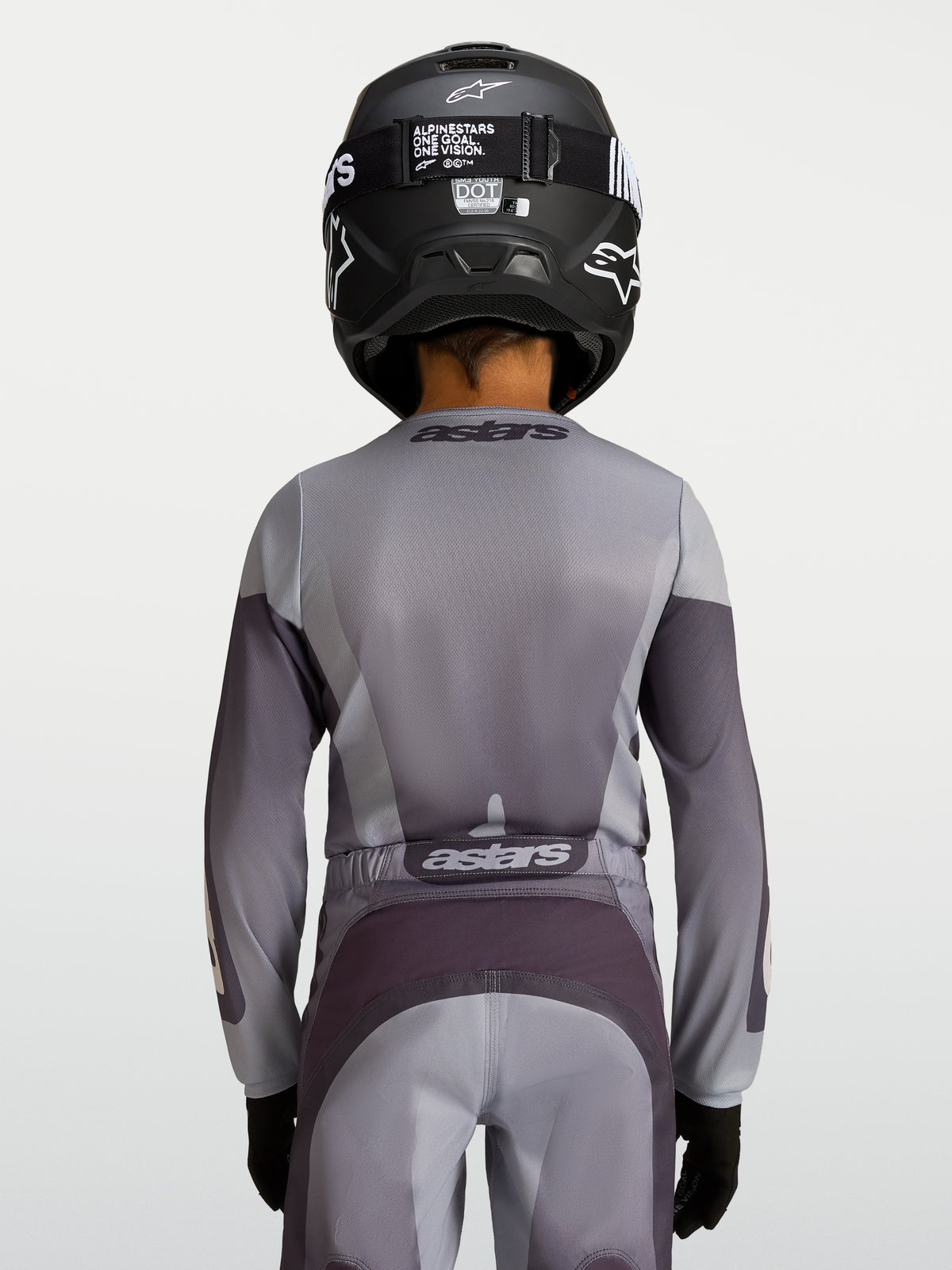 Alpinestars 2027 Fluid Amber trøje til ungdom, motocross-trøje i grå og sand, set bagfra på en ung rytter, åndbart og let poly-stof til off-road kørsel og MX-performance