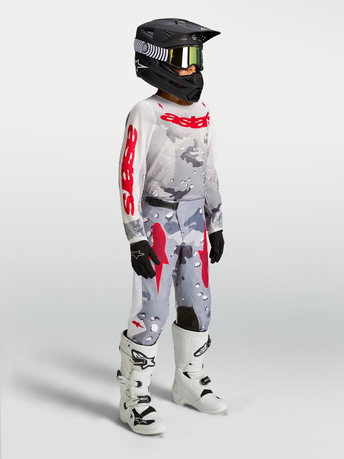 Alpinestars Ungdom Fluid Lone udstyrssæt, grå camo og rød motocrosstrøje og bukser på rytter med hvide støvler.