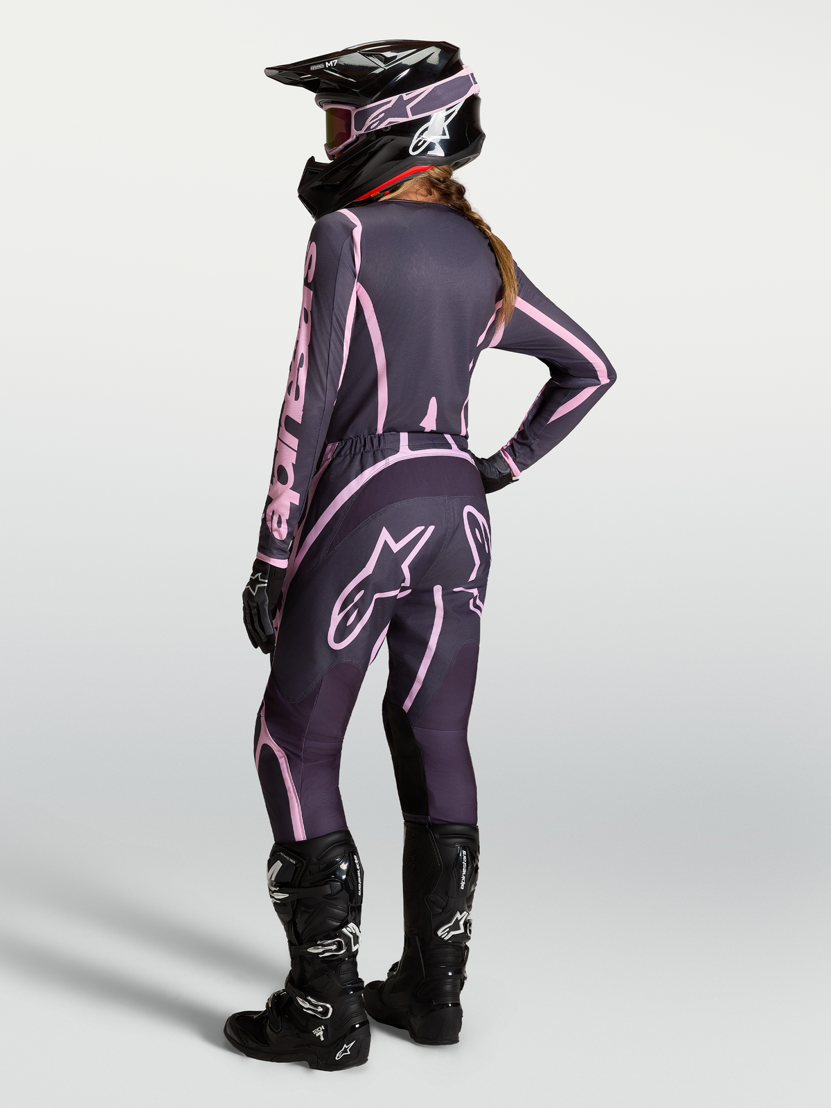 Alpinestars Stella Fluid Apex V2 trøje og udstyrssæt, motocross-udstyr til kvinder, grå og pink med sorte motorcykelstøvler, set bagfra.