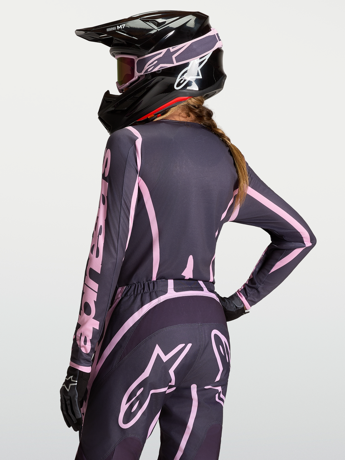 Alpinestars Stella Fluid Apex V2 Trøje, motocross-trøje til kvinder, grå og pink, fugttransporterende poly-stof, vist bagfra med hjelm og bukser