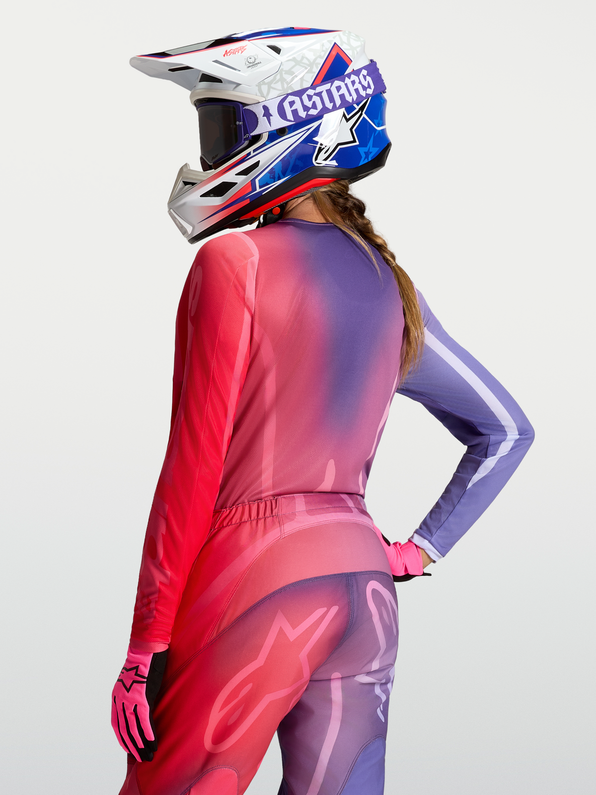 Alpinestars Stella Fluid Kepler trøje, motocrossudstyr til kvinder, lilla og rød gradient, set bagfra på model med hjelm, åndbart polyfabric og atletisk pasform.