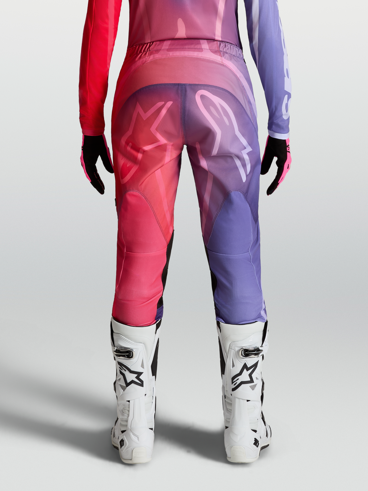 Alpinestars Stella Fluid Kepler Bukser, dame-motocrossbukser i lilla og rød, set bagfra med hvide støvler, præformet ergonomisk pasform.