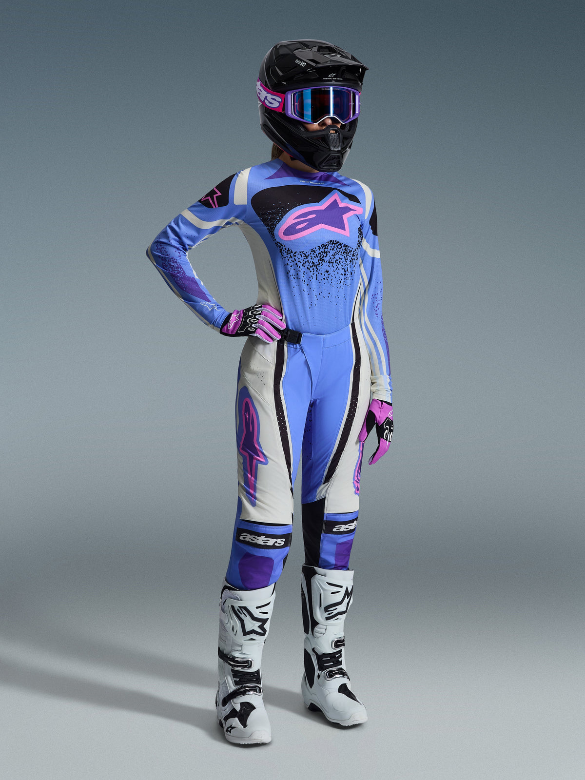 Alpinestars 2026 Stella Techstar Nomur udstyrssæt, motocross-udstyr til kvinder med lyseblå trøje og lyserødt Astar-logo, matchende bukser med hvide og sorte paneler, sort hjelm med lyserøde og lilla goggles, lyserøde handsker og hvide motocross-støvler