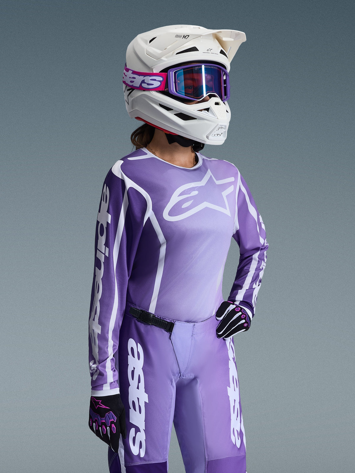 Alpinestars 2026 Stella Fluid Apex Gear Set til damer, lilla og lavendelfarvet motocross-trøje og bukser, båret af en kører med hvid hjelm og lilla goggles, med markant hvid Alpinestars-branding og logoer