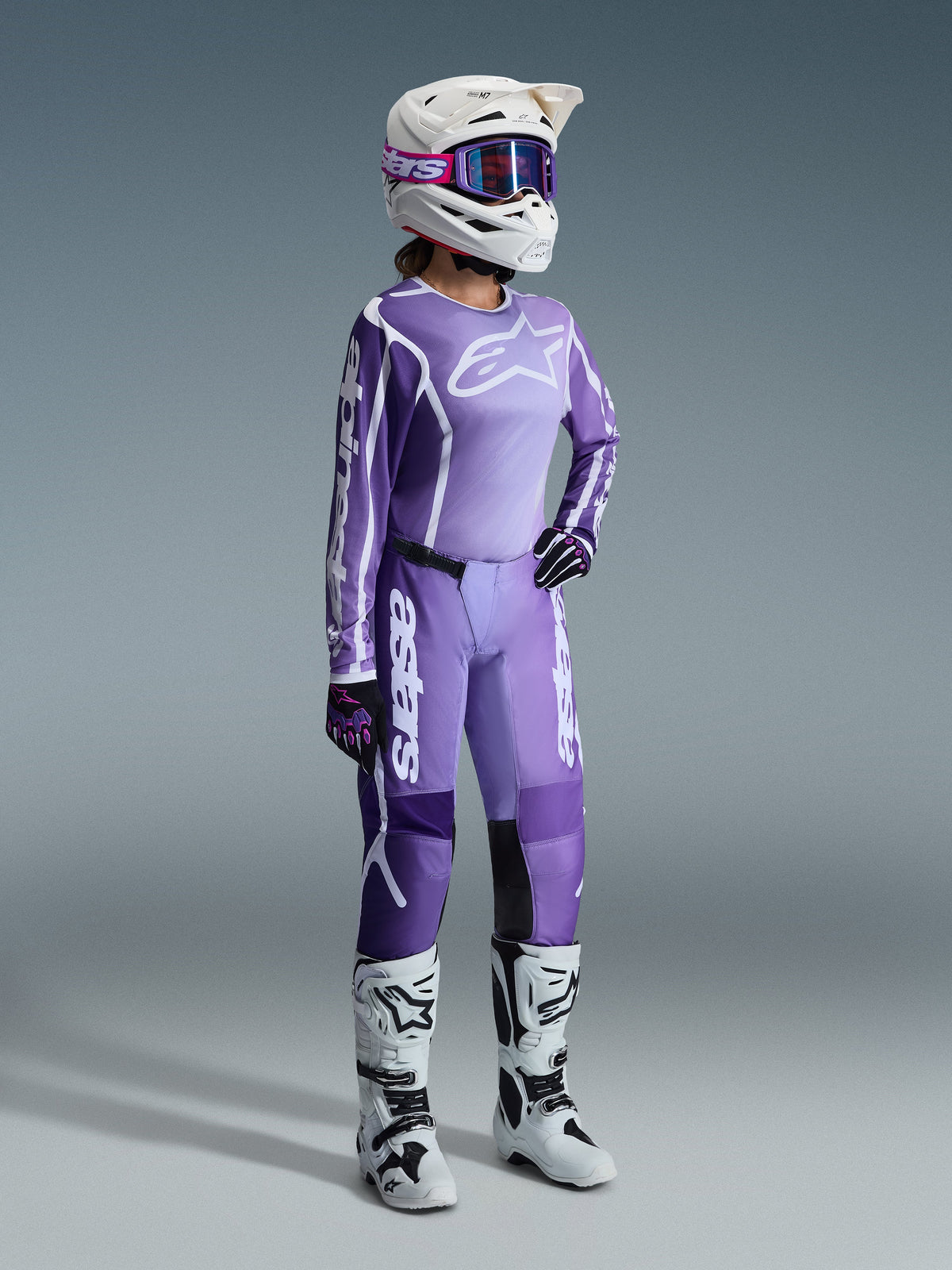 Alpinestars 2026 Stella Fluid Apex Gear Set, lilla og lavendel, kvindelig motocrosskører iført matchende trøje og bukser, hvid hjelm med lilla goggles, hvide og sorte støvler, sorte og lilla handsker, komplet performance-outfit til off-road racing til kvinder