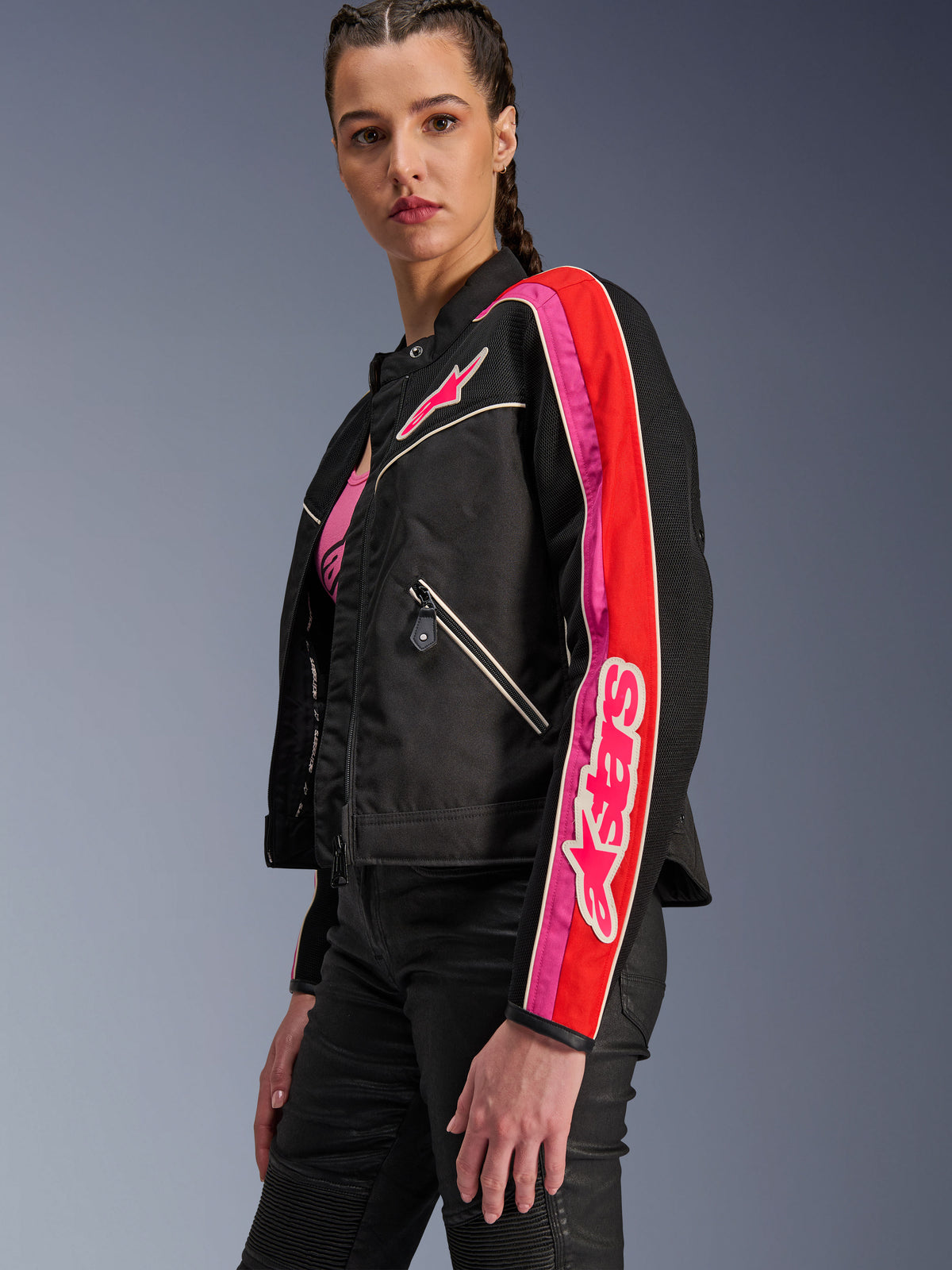 Alpinestars Stella T-Dyno Air jakke til damer, motorcykeljakke til kvinder, sort med klare røde og fuchsia detaljer, båret med sorte bukser, med lyserødt Astars-logo på brystet og ærmet, skræddersyet bikerpasform med mesh-paneler til ventilation.