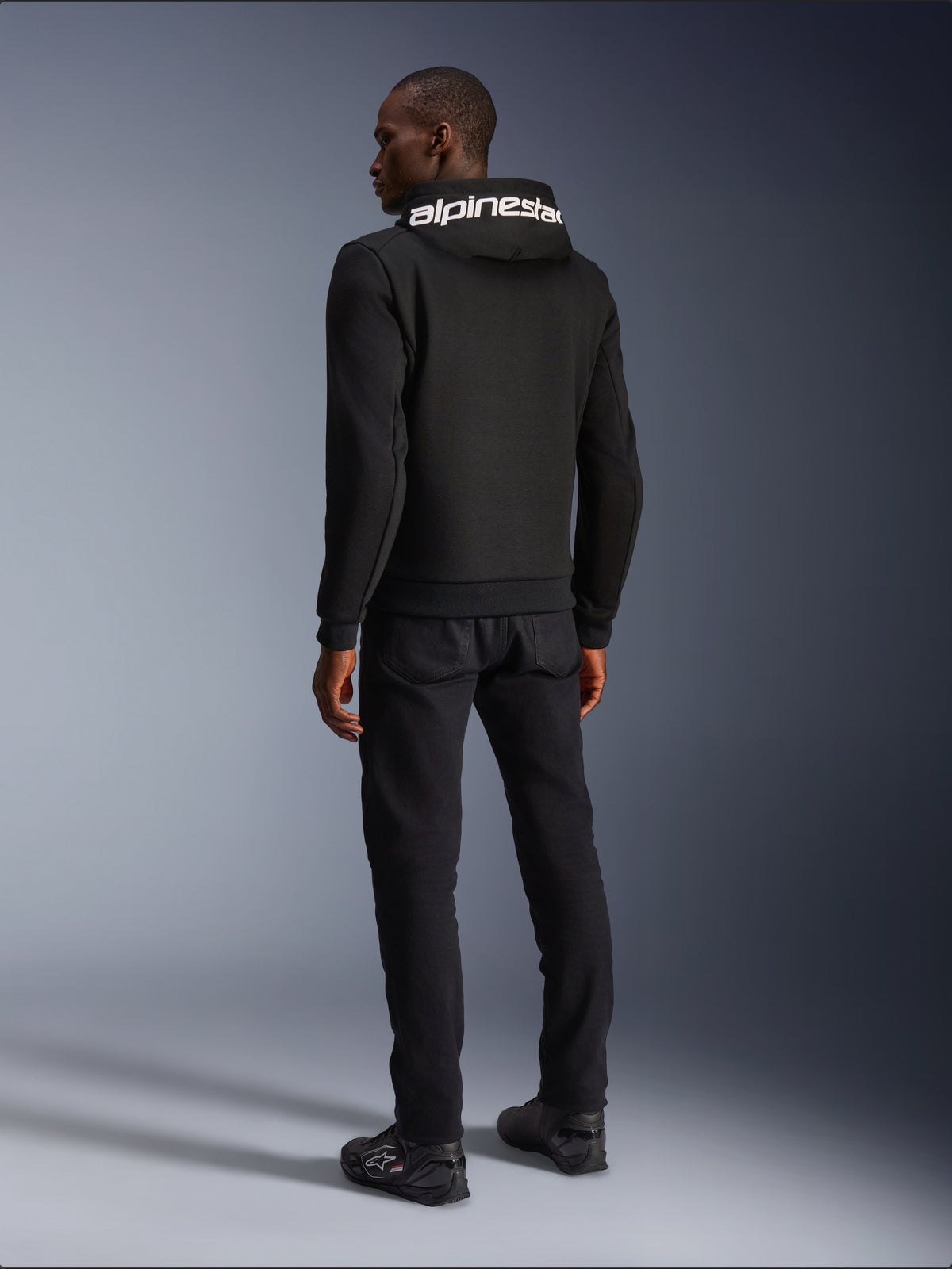Alpinestars Chrome V2 Sport hættetrøje, urban motorcykeljakke til herrer, sort og hvid, set bagfra med hvidt logo på hætten, atletisk silhuet.