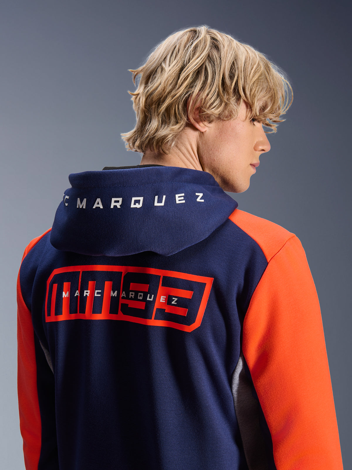 Alpinestars MM93 Chrome V2 Sport Hoodie, navy blue with vibrant orange sleeves, large red MM93 logo and Marc Marquez branding on the back, white lettering on the hood, casual urban motorcycle riding hoodie.