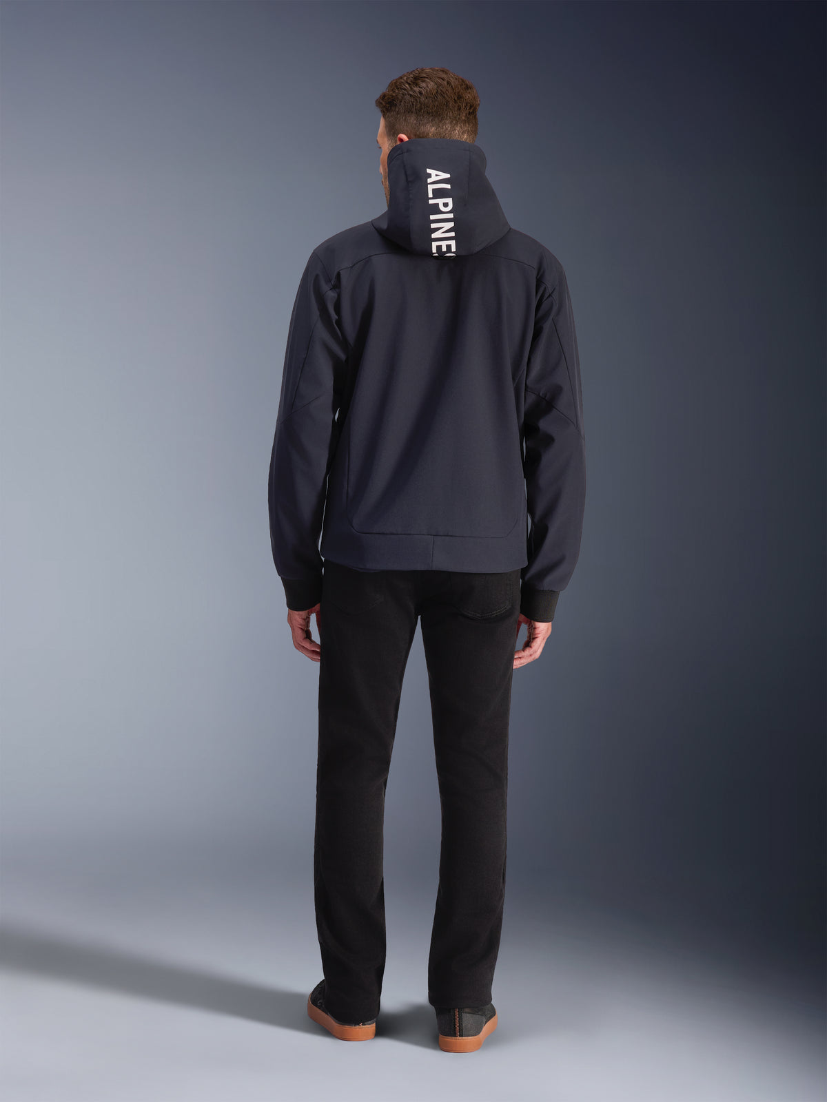 Alpinestars Radium Tech hættetrøje, vindtæt urban motorcykeljakke til herre, sort med hvidt logo på hætten, set bagfra.