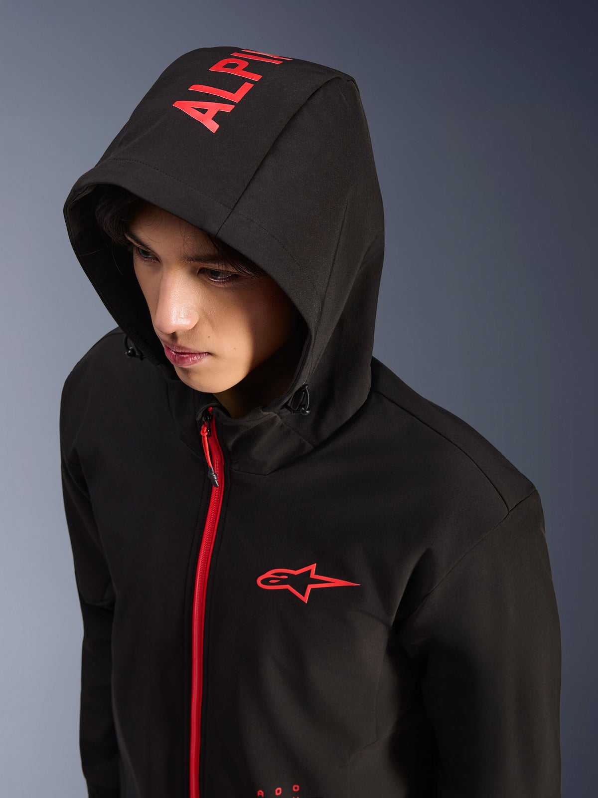 Alpinestars Radium Tech Hoodie, sort og postkasserød, urban teknisk shell-motorcykelhættetrøje, rødt Alpinestars-logo på brystet og rød branding på hætten, klar rød lynlås, moderne motorsport-inspireret streetwear