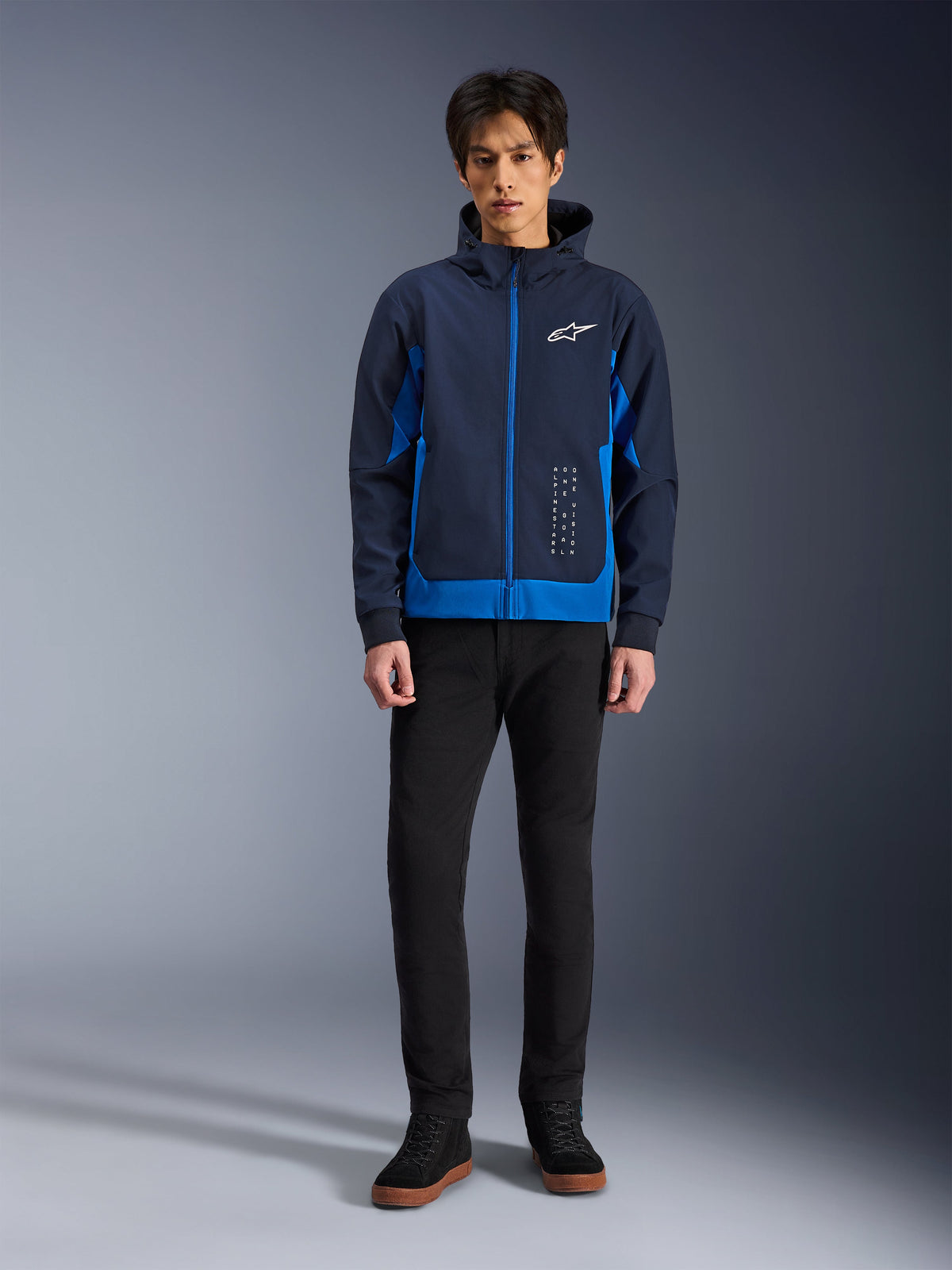 Alpinestars Radium Tech Hoodie, Night Navy og Royal Blue urban motorcykelhættetrøje, vindtæt teknisk skal, afslappet streetwear-design båret med sorte bukser og high-top sneakers, hvidt logo på brystet