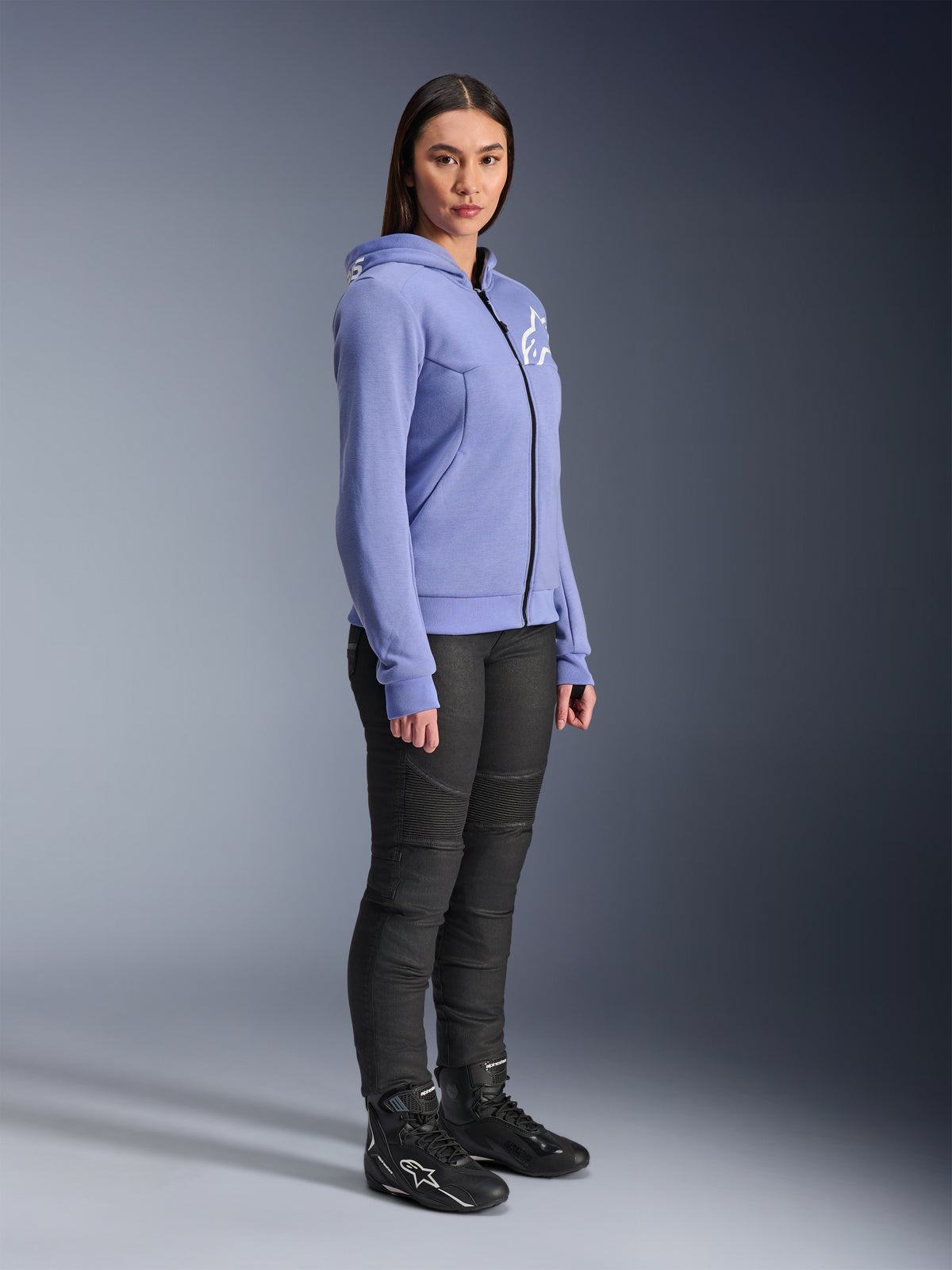 Alpinestars Stella Chrome V2 Sport Hoodie til kvinder, motorcykel-hættetrøje i blåviolet med hvidt Alpinestars-logo på brystet, båret af en model med sorte MC-bukser og sorte motorcykelstøvler, urbant køreudstyr til kvinder