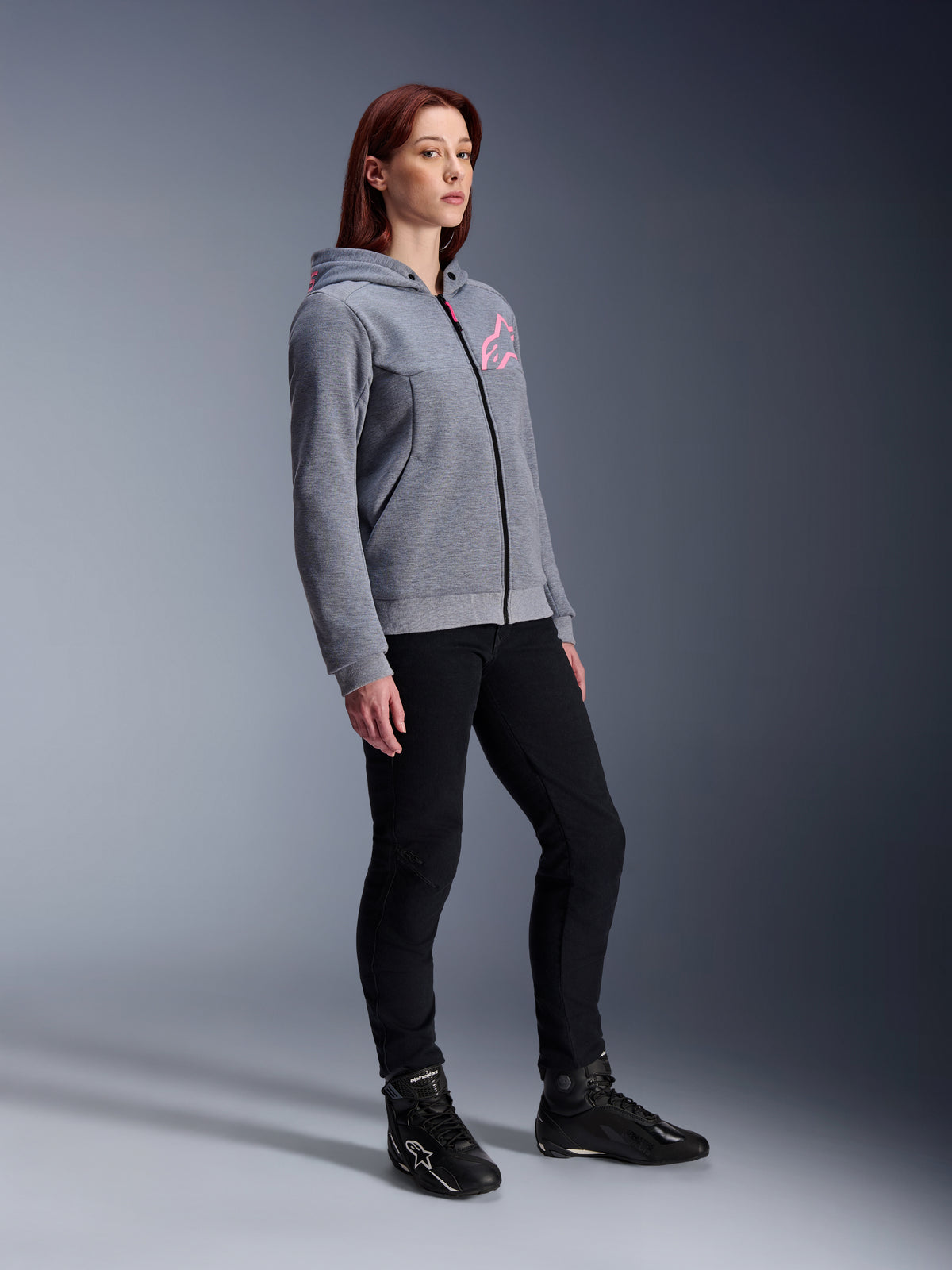 Alpinestars Stella Chrome V2 Sport hættetrøje, motorcykel-hættetrøje til kvinder, gråmeleret og neon pink, kombineret med sorte kørebukser og sorte støvler, afslappet urbant køreudstyr
