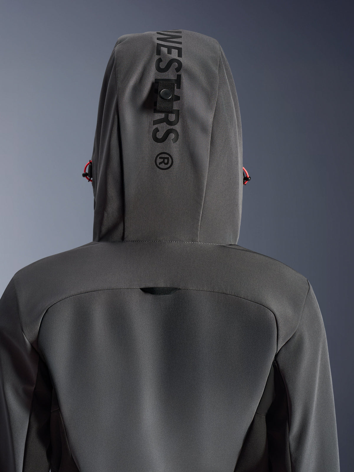 Alpinestars Stella Radium Tech Hoodie til kvinder, Deep Gray Black, nærbillede bagfra der viser hætten med lodret branding og fastgørelsesløkke, røde detaljer på snoretrækket, slidstærk 3-lags vindtæt tekstilkonstruktion til bykørsel på motorcykel