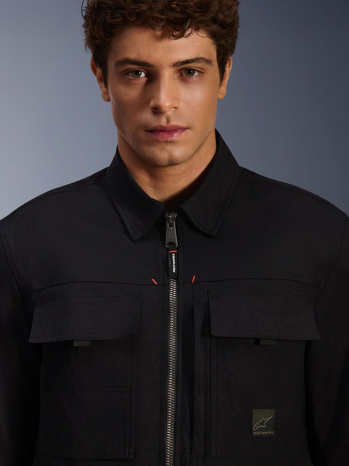 Alpinestars Bryon Water Resistant Overshirt, Black, close-up view of front zipper and chest pockets, durable waxed canvas texture, minimalist urban design with branded accents and woven logo label