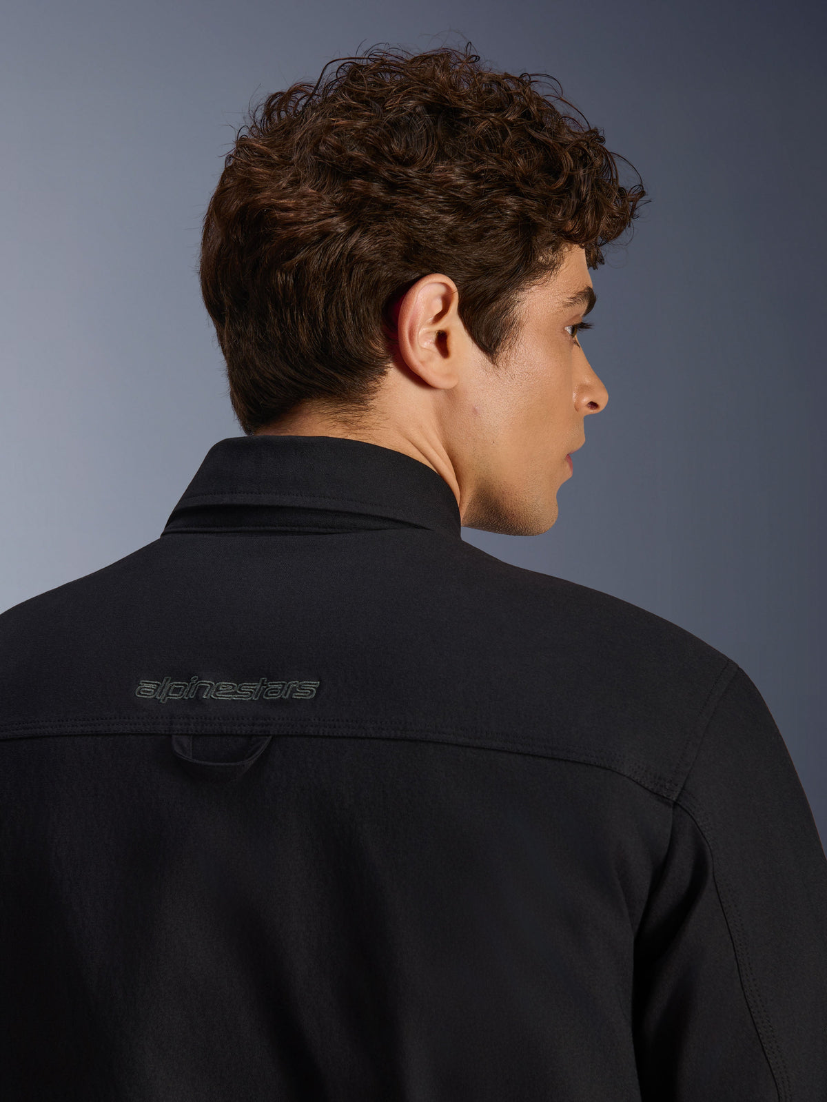 Alpinestars Bryon Water Resistant Overshirt, urban motorcycle jacket, Black, close-up of back shoulder area with embroidered logo and hanging loop, water-resistant waxed canvas construction.