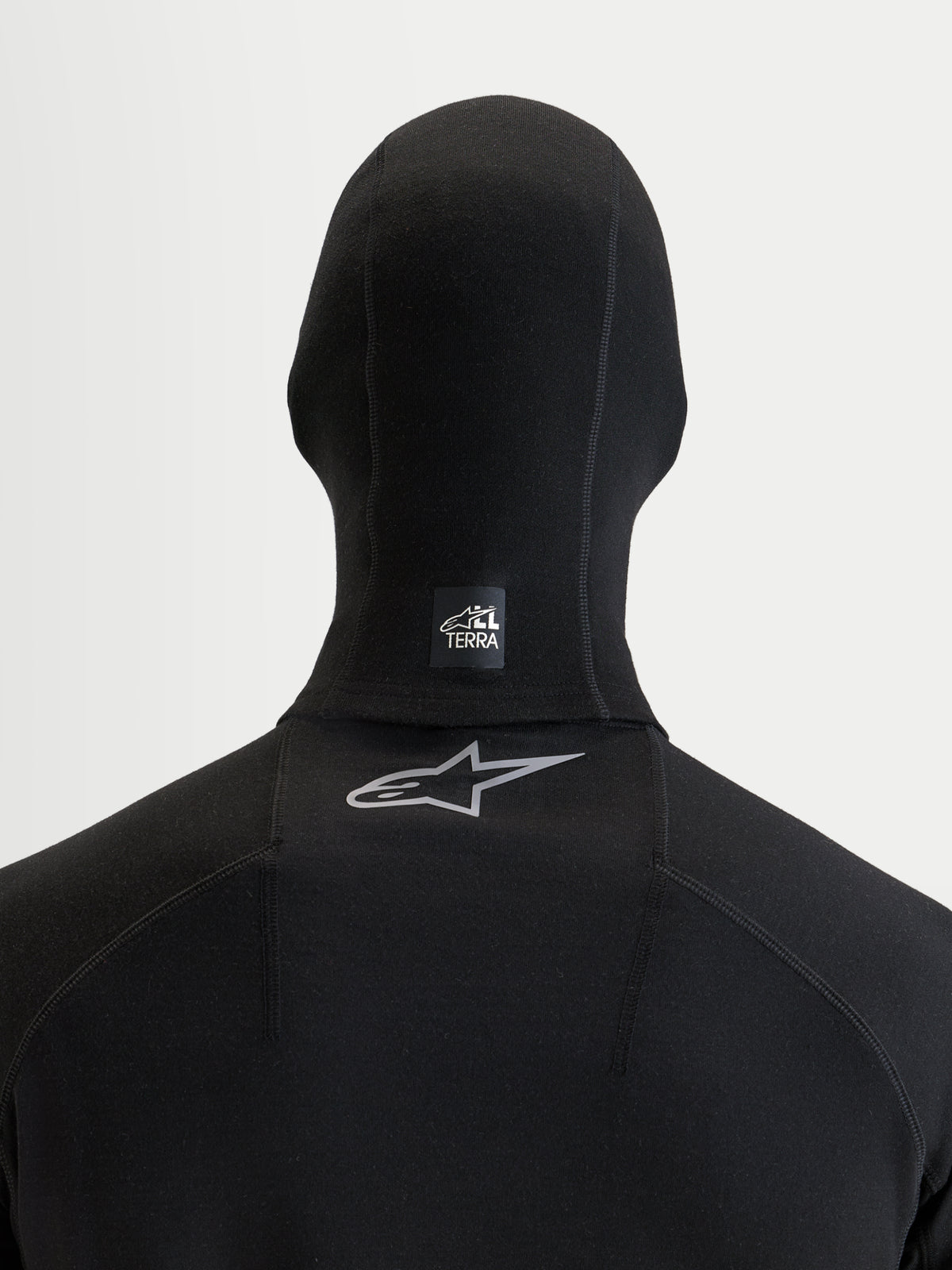 Alpinestars At 8 Merino Balaclava, sort motorcykel-balaclava set bagfra der viser et All Terra-mærke på nakken og reflekterende Astar-logo på øvre ryg, termisk merinould-blanding til eventyrkørsel i koldt vejr